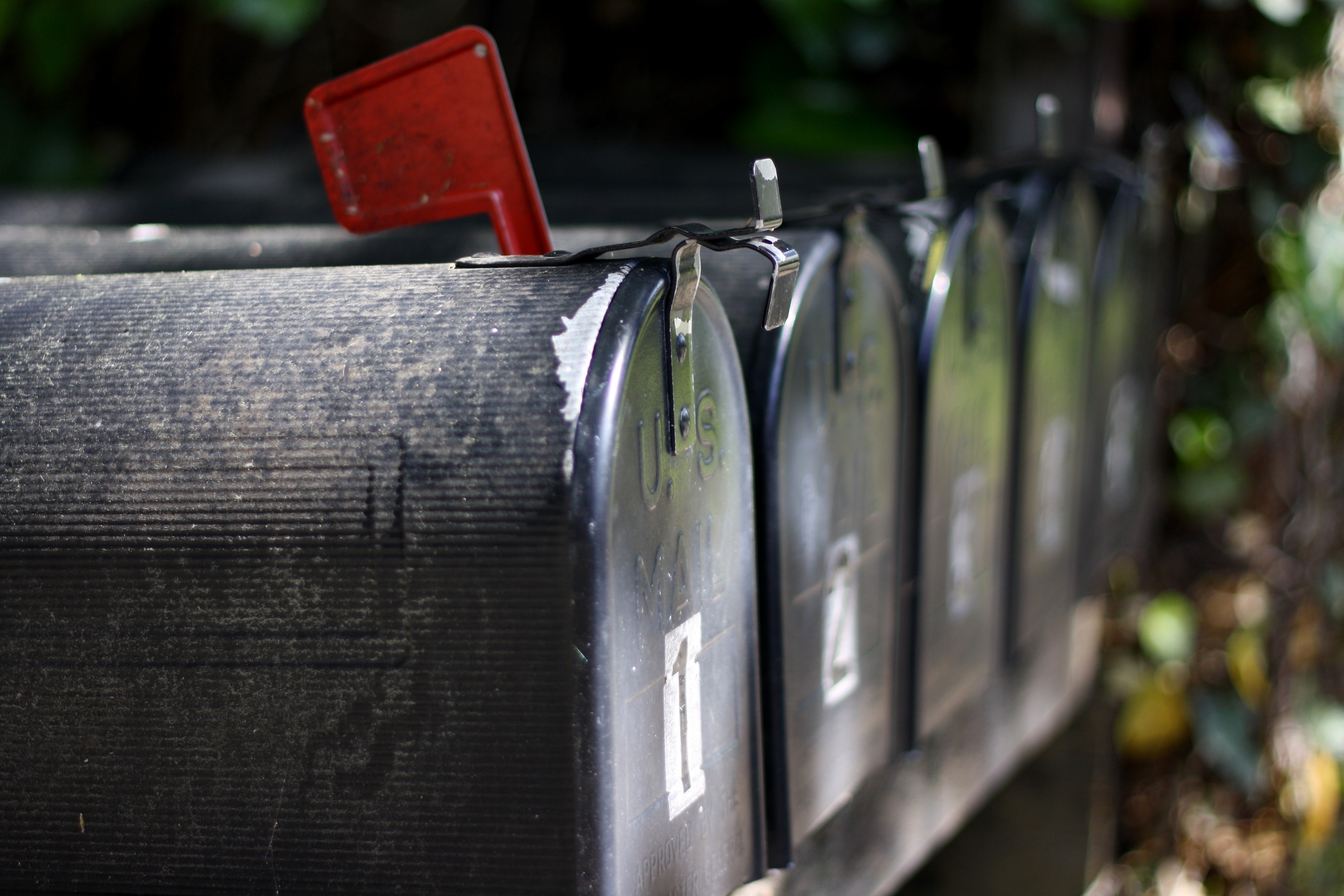 Svarta postlådor på rad med röd flagga för att markera att kommit finns post