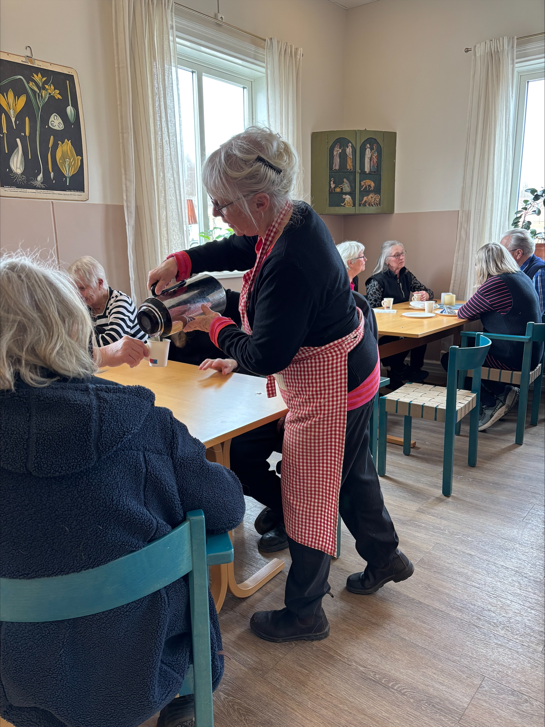 Kvinna serverar kaffe vid fikabord