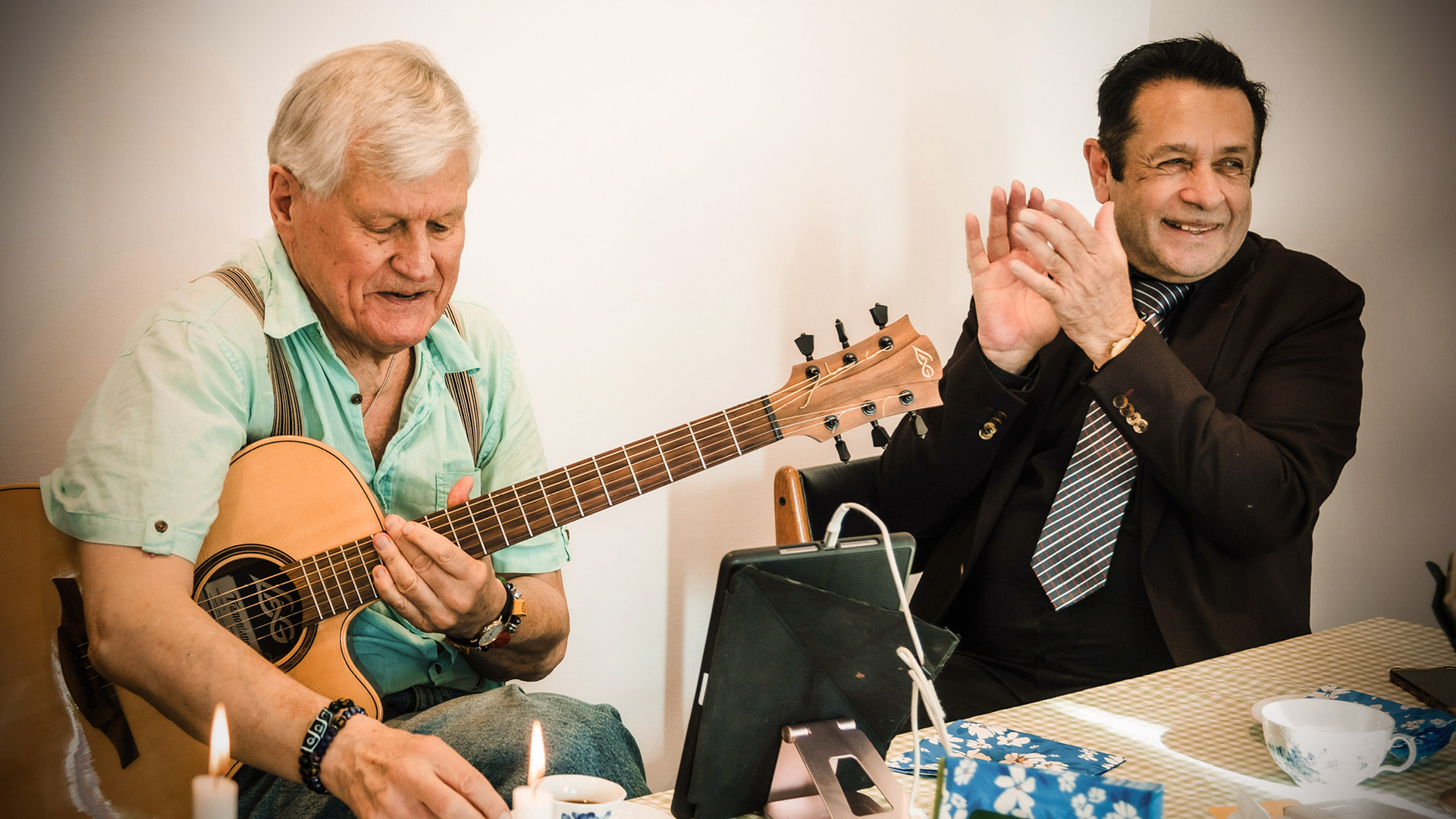 Män klappar, skrattar och spelar gitarr.