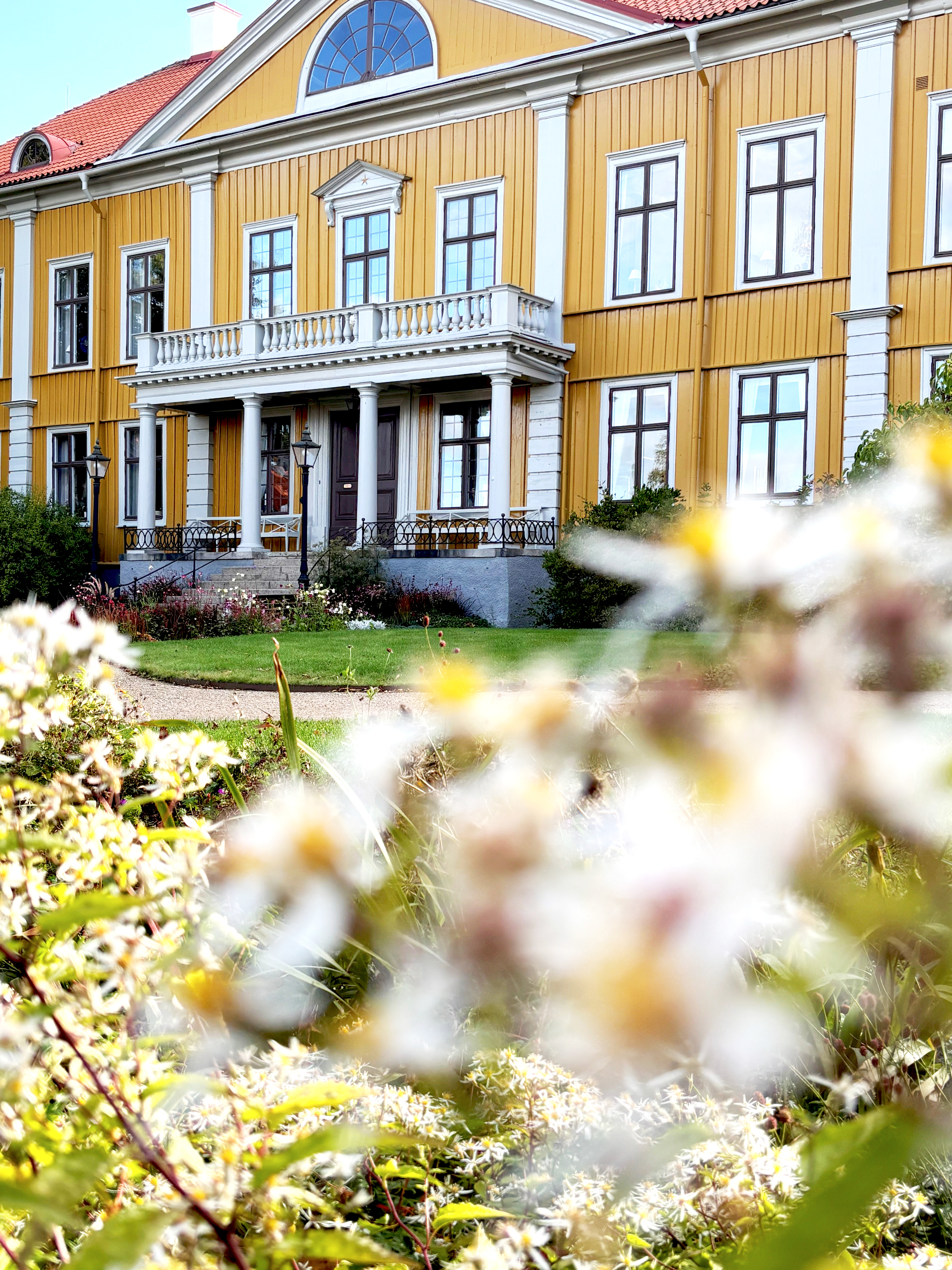 Biskopsgården Östrabo med vita höstblommor i förgrunden