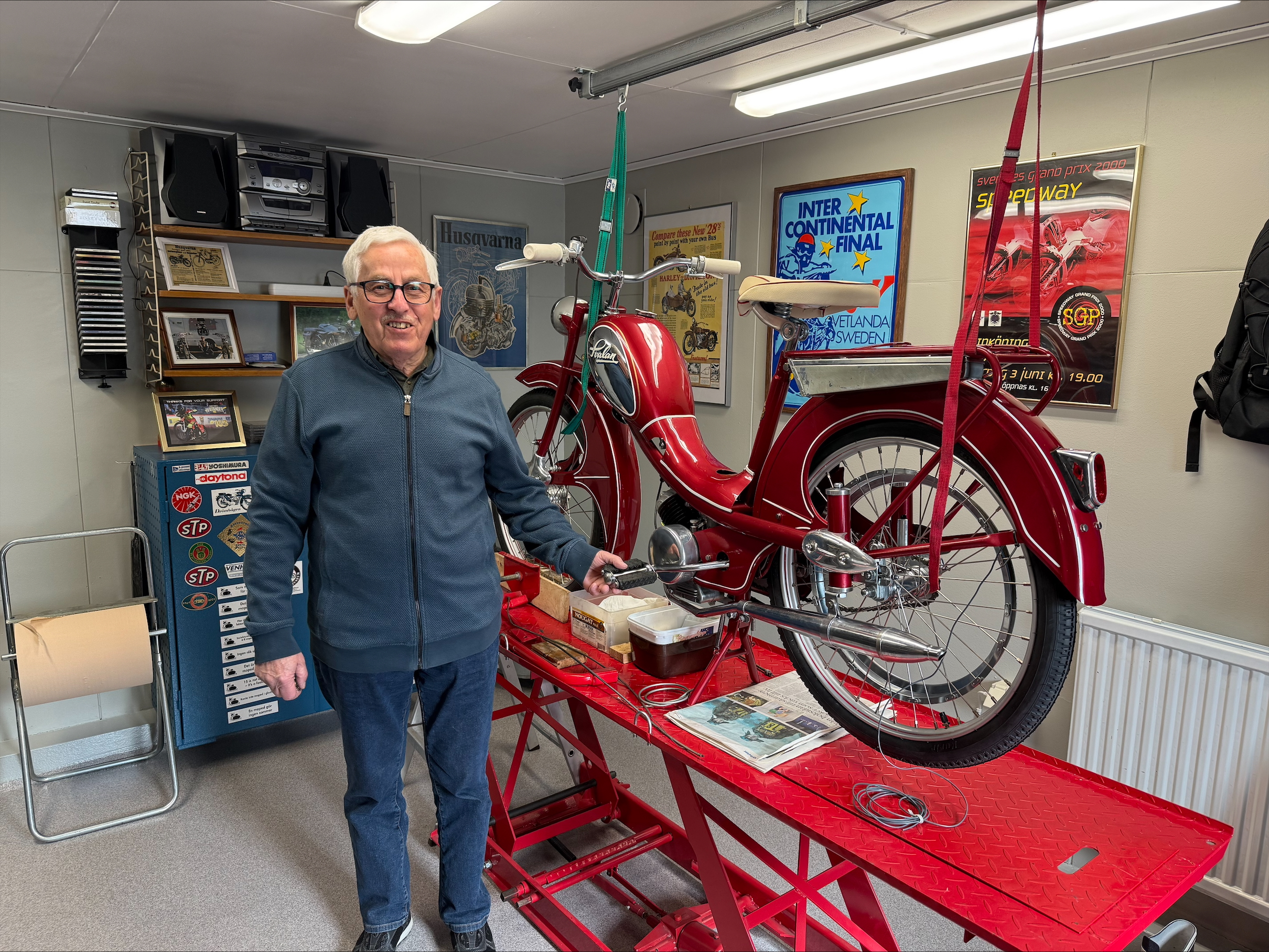 Terje Henriksson står i sitt garage, intill en röd moped som han renoverat.