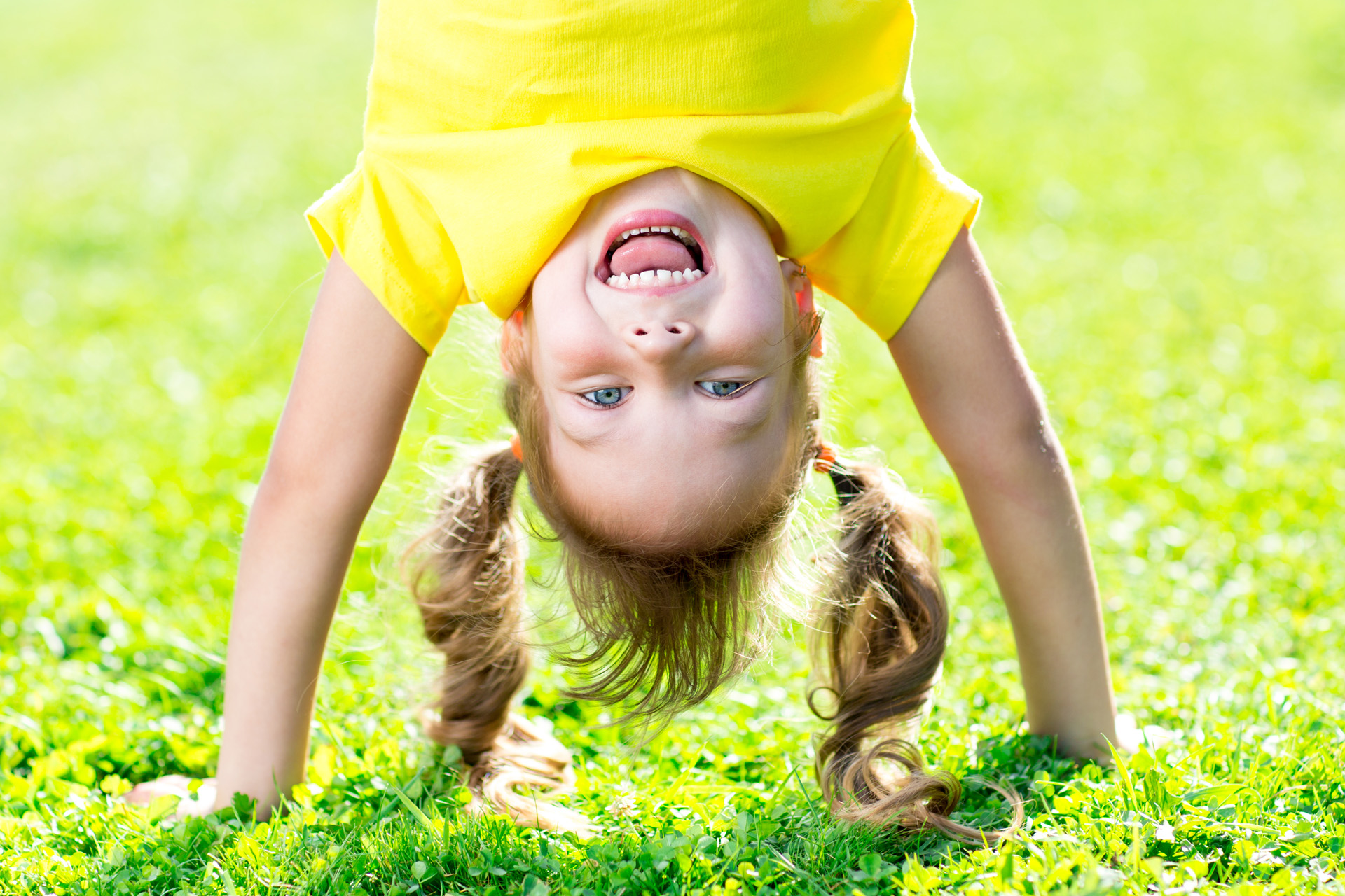 Glad flicka som står på händerna.