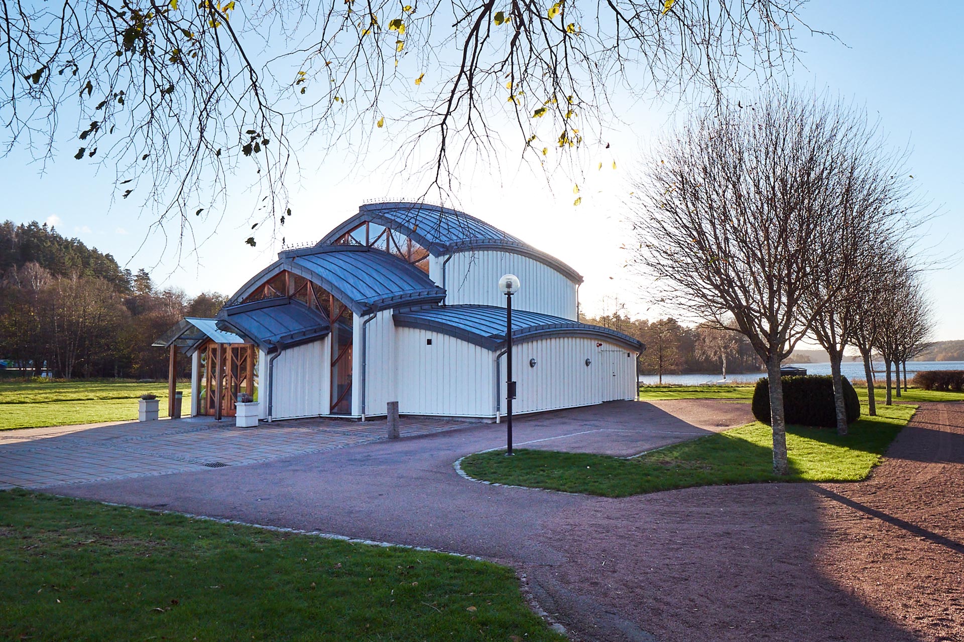 Gröenkapellet i solnedgången. Ett mindre modernt kapell omgivet av gräsmatta och några träd.