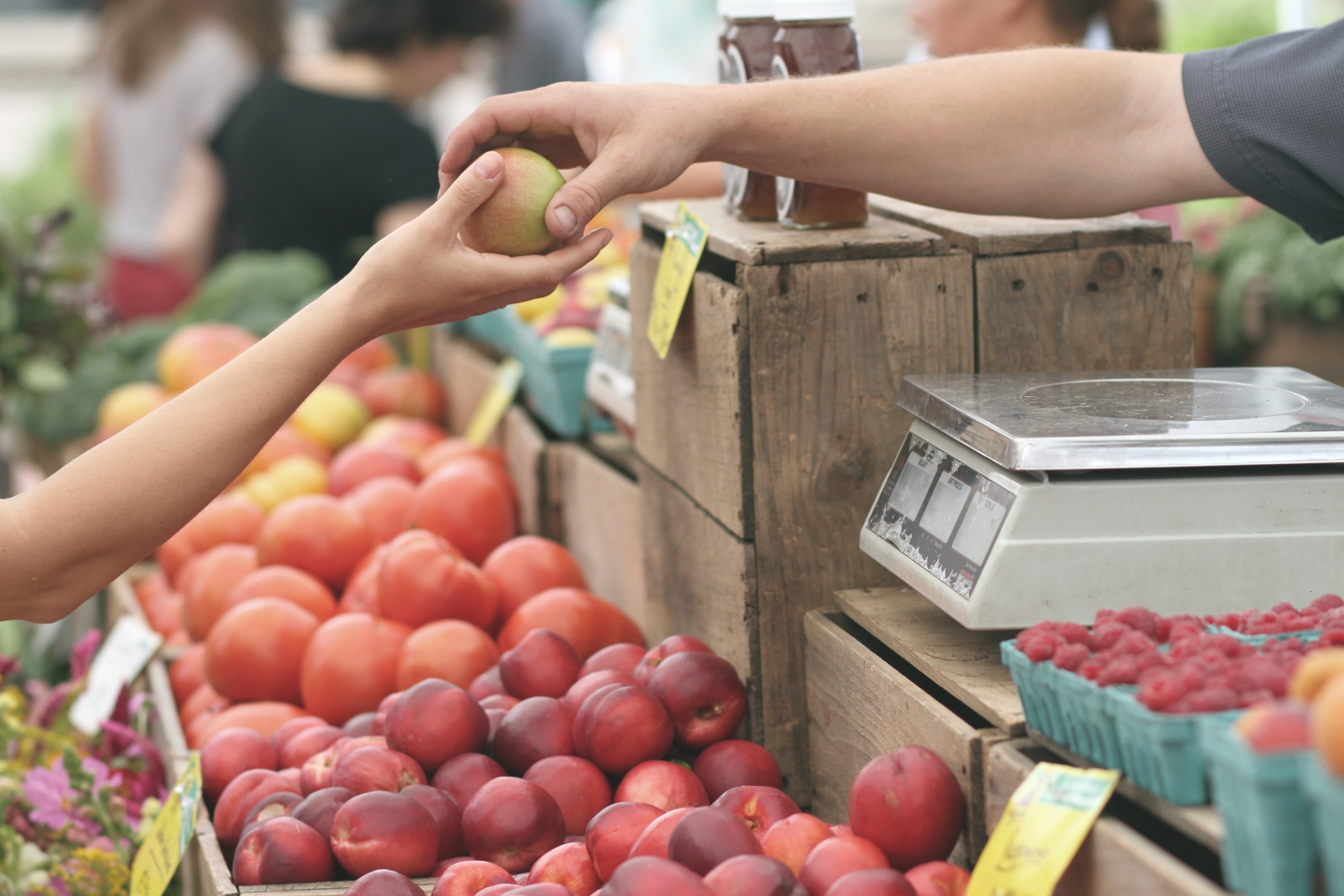 Någon köper frukt i ett marknadsstånd