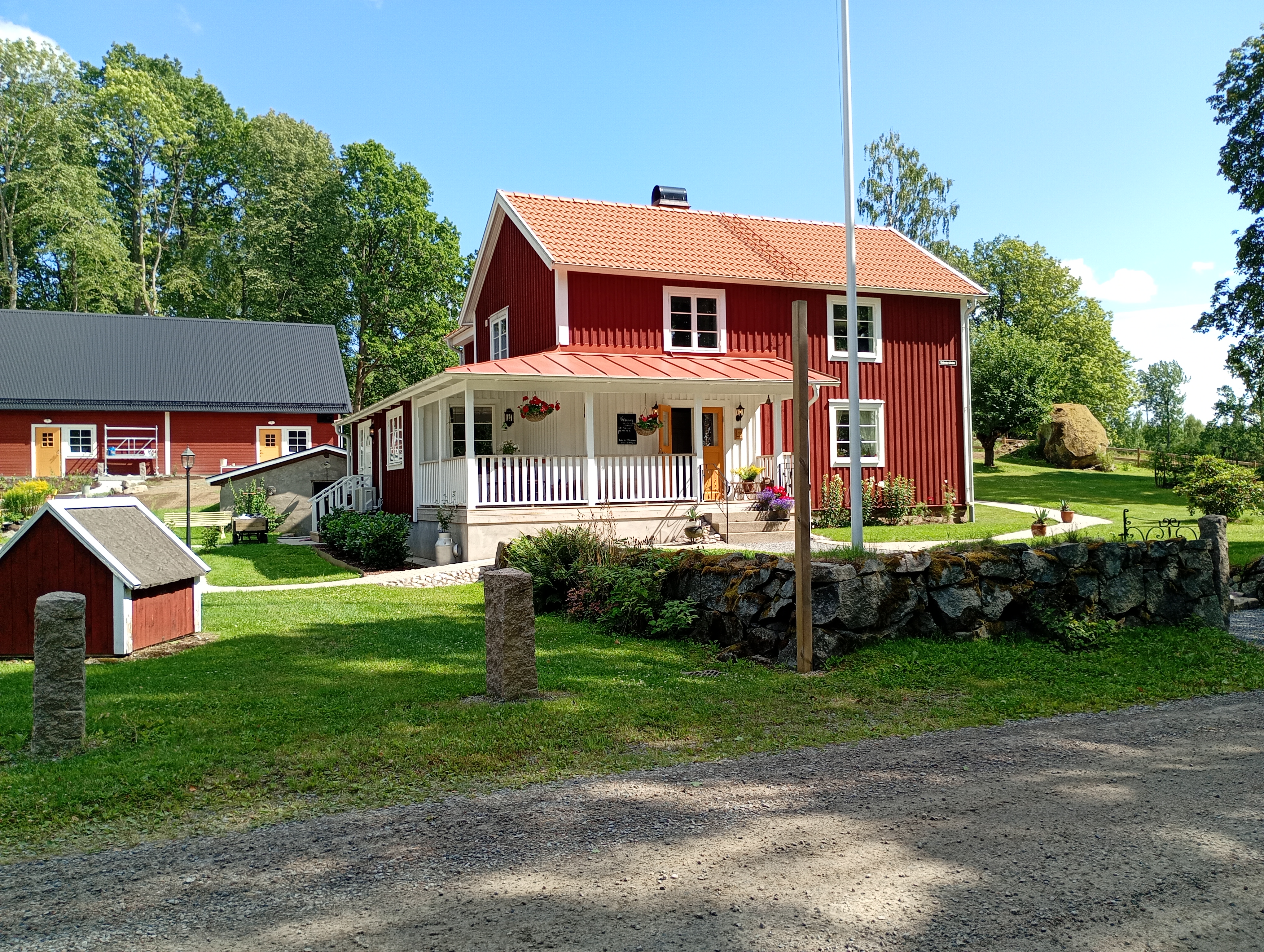 Några röda trähus med vita knutar bakom en stenmur