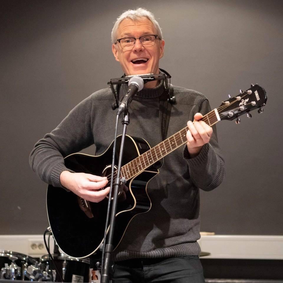 En glad man med gitarr och munspel