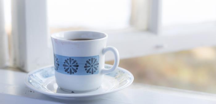 En kopp med kaffe står vid ett öppet fönster