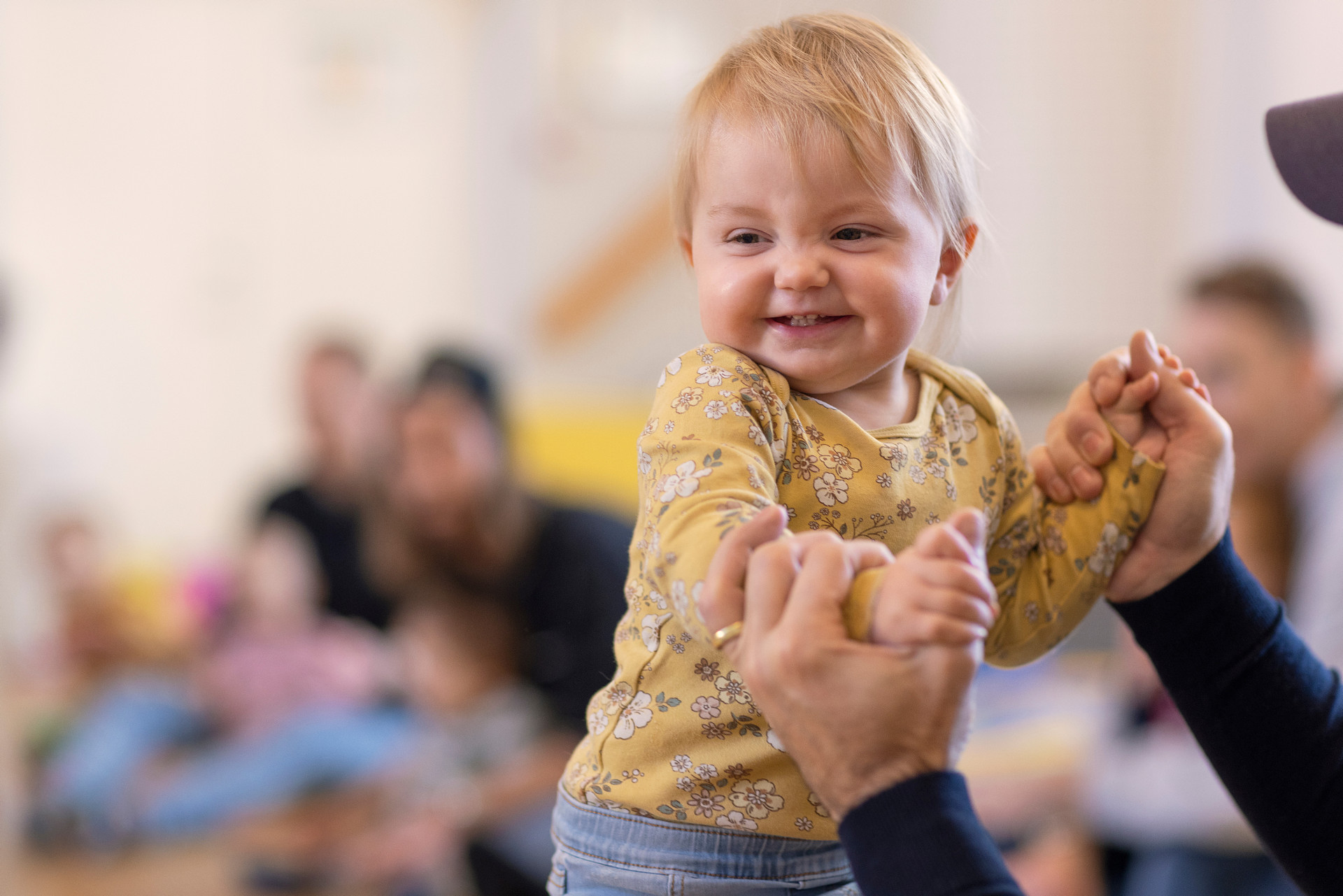 Ett glatt barn i 2-årsåldern håller sin pappas hand. 