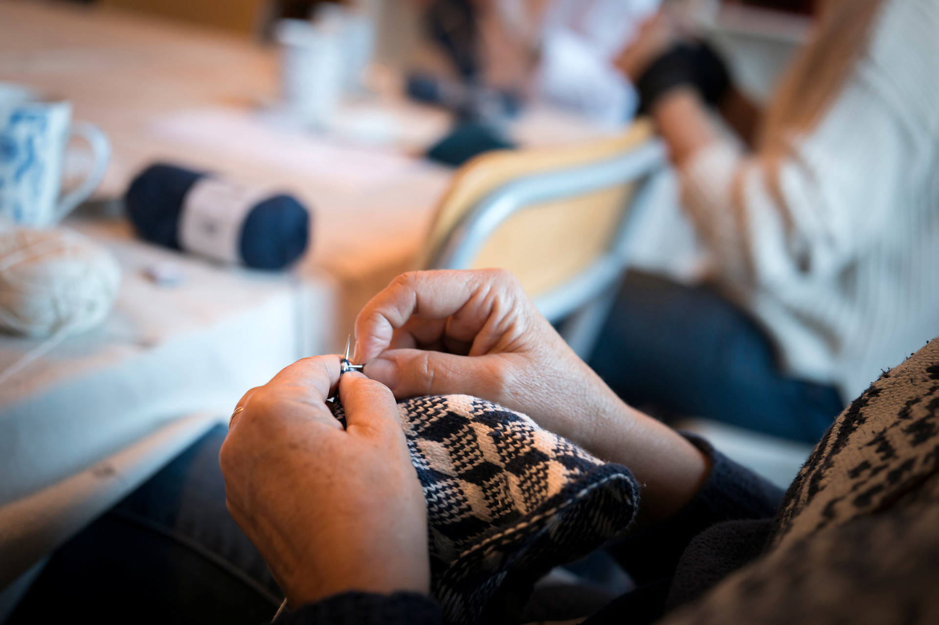 Närbild på händer som virkar ett par blåvita vantar. 