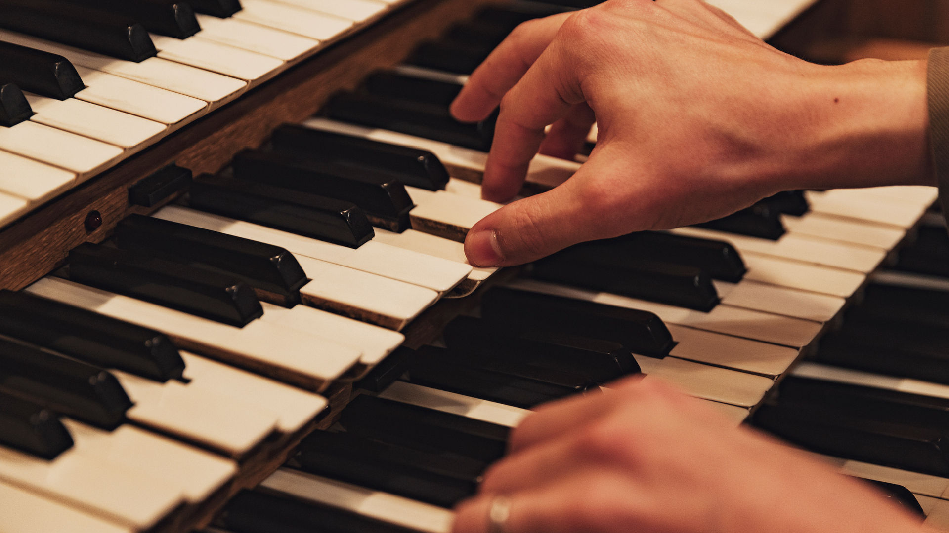 Två händer som spelar på orgelns tangenter