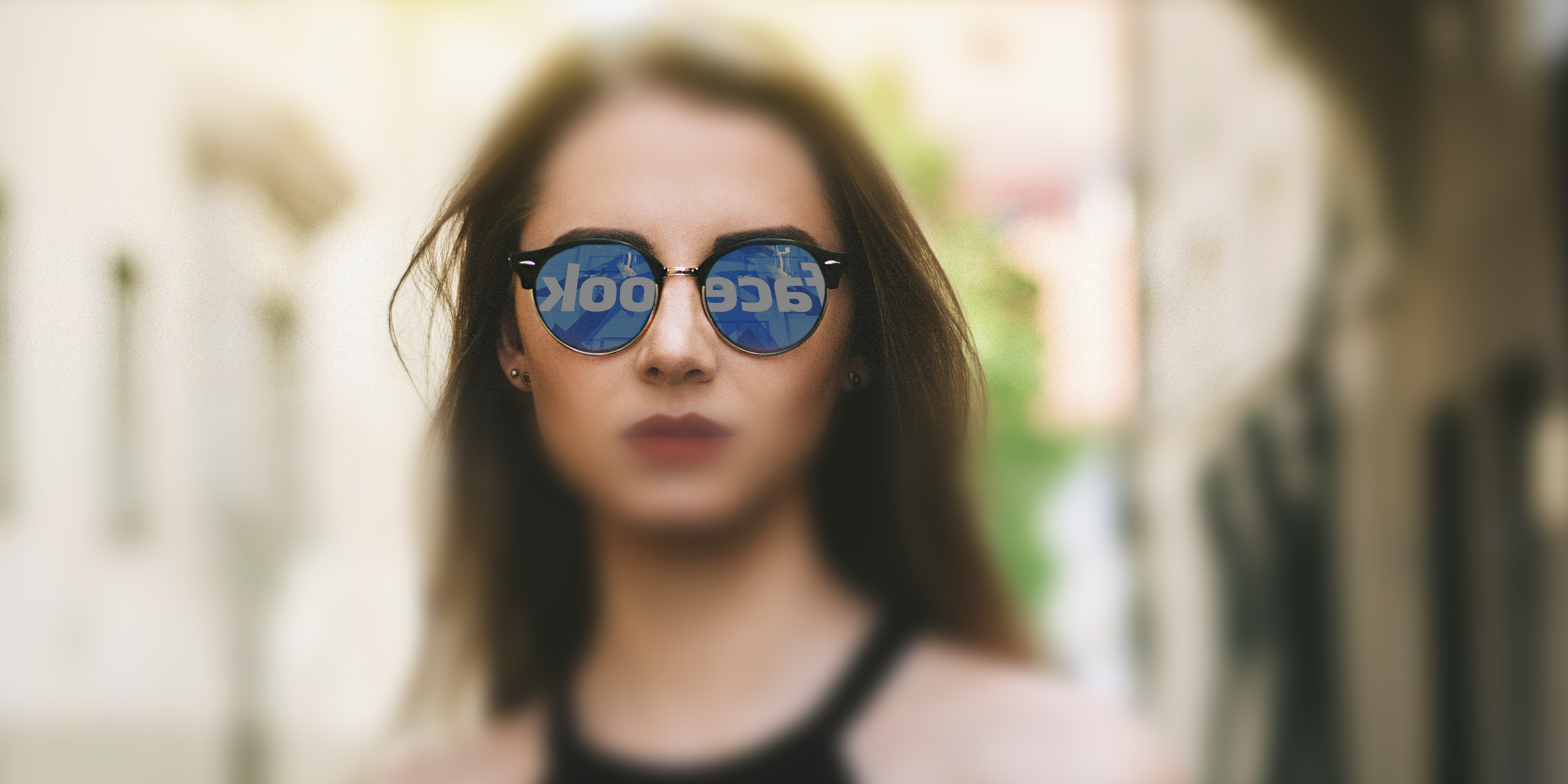 En tjej med solglasögon där facebookloggan reflekteras