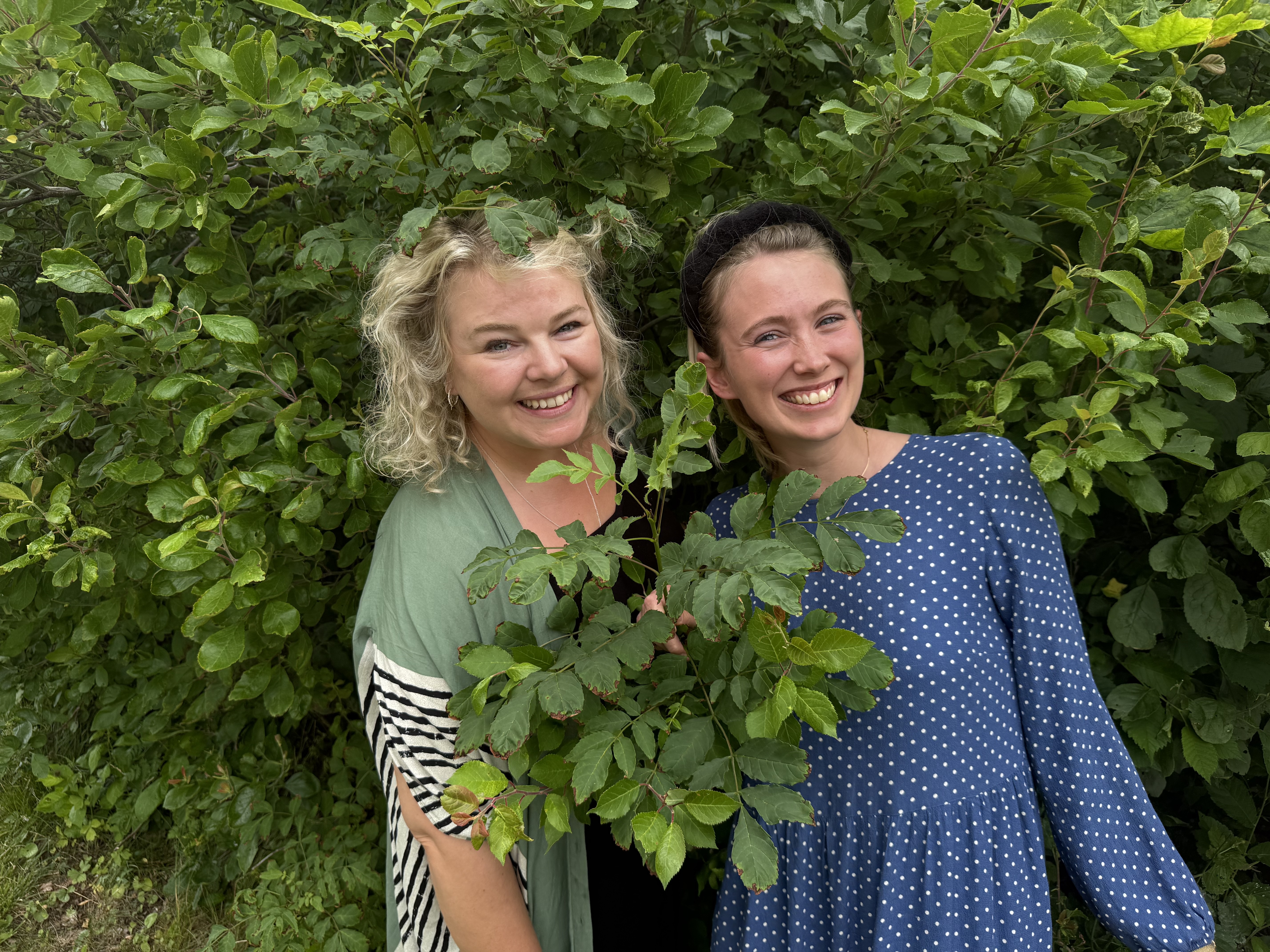 Rebecka och Klara framför grön buske