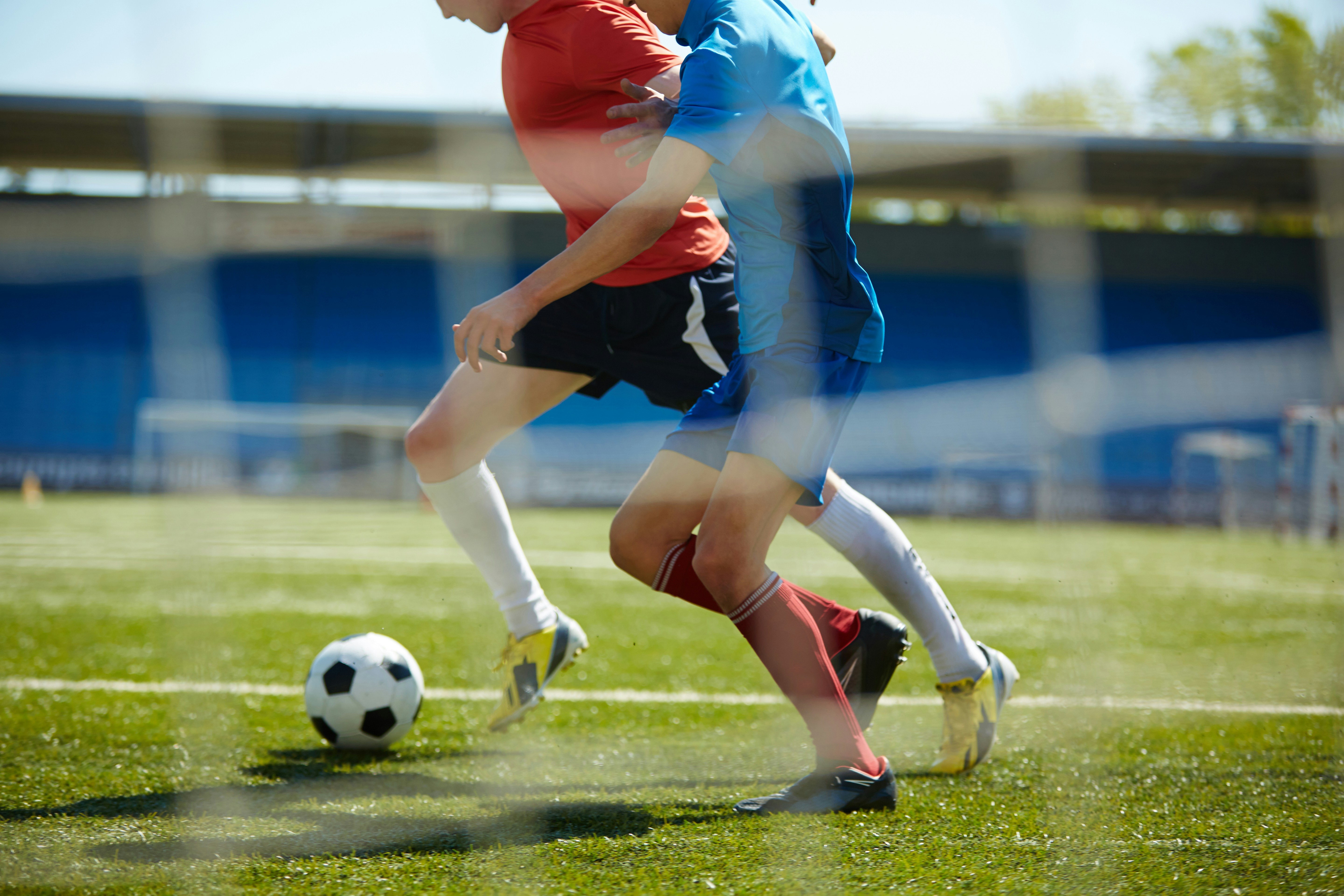 Benen och fötter av två fotbollsspelare med boll