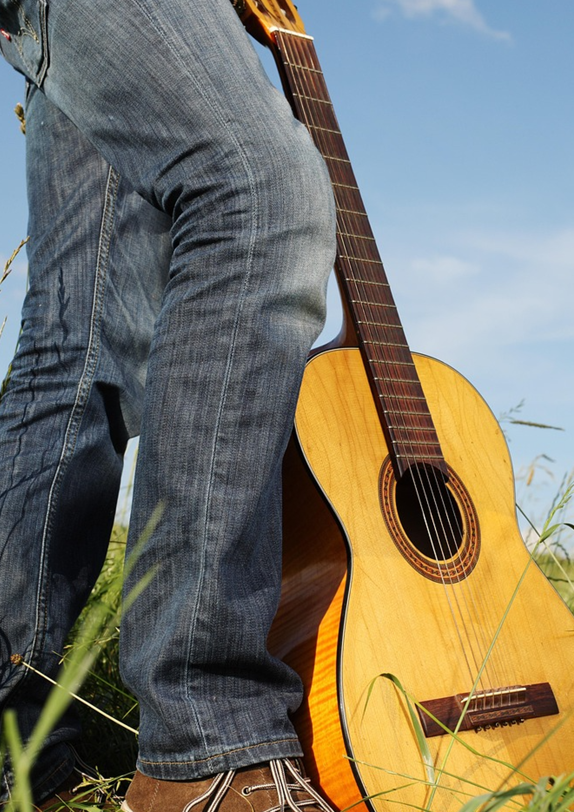 Gul gitarr på ett fält med någon i jeans