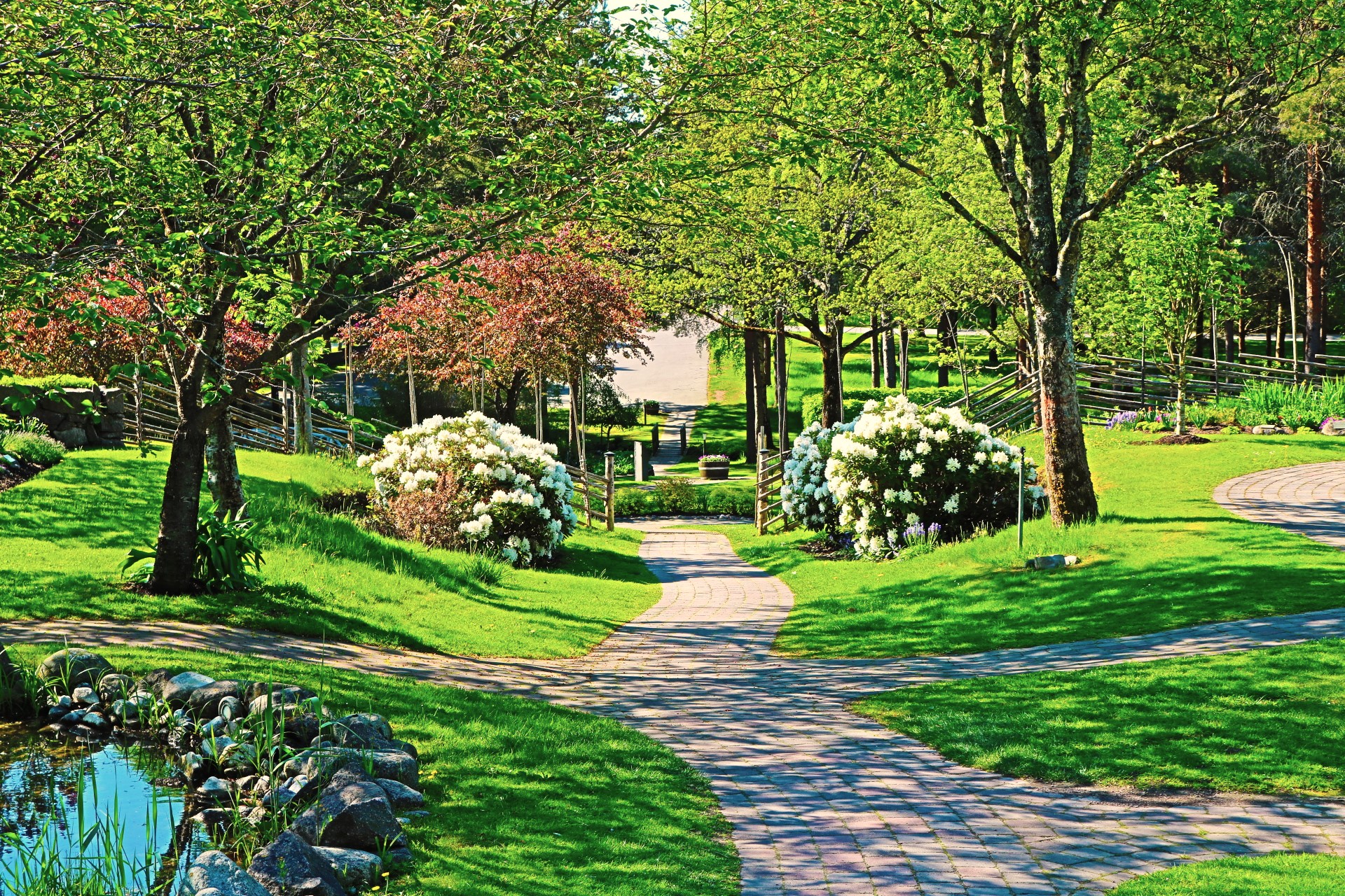 Griftegården i sommarskrud, grönt gräs, buskar och träd. 