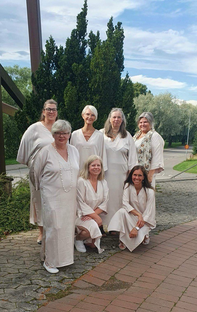 Kvinnor i grupp i beiga klänningar.