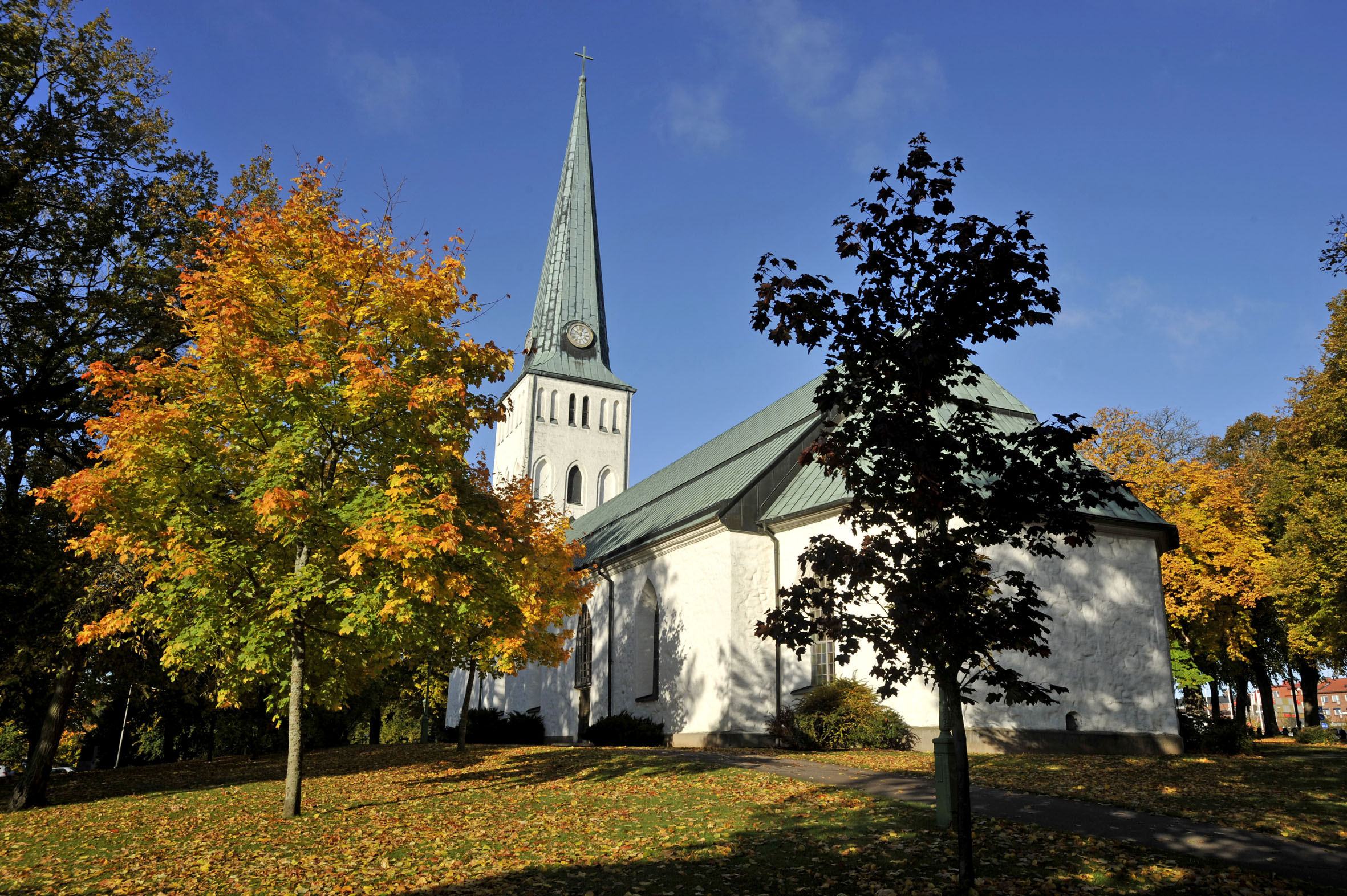 Vit kyrka med träd i höstskrud