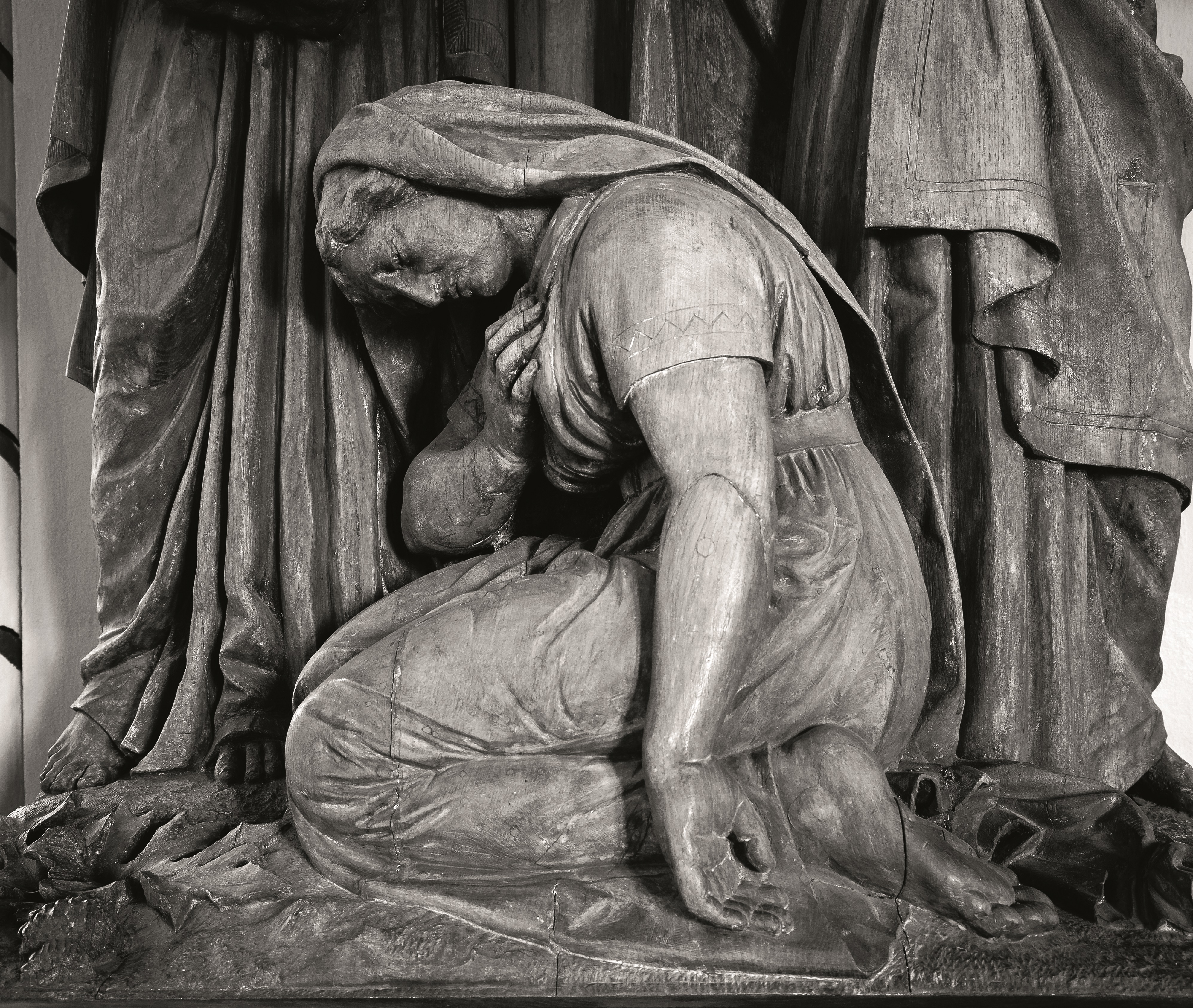 Svartvit bild av staty av kvinna som böjer sig knäfallande.