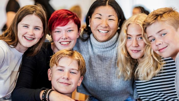 Ett gäng tjejer och killar i 15-årsåldern håller om varandra och skrattar.
