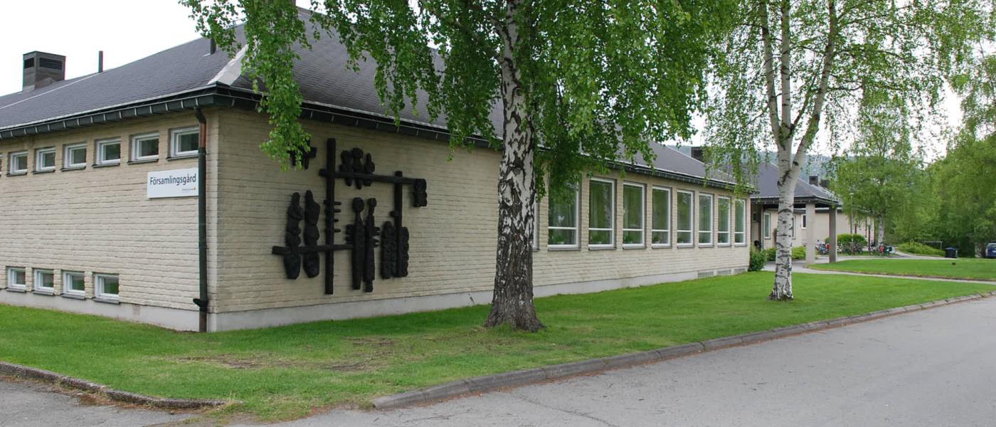 Framsidan av Sollefteå församlingsgård. Byggnaden omgiven av försommargröna björkar.