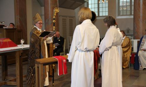 Biskop Eva Nordung Byström, i biskopsskrud, viger tre personer till tjänst. Platsen är Härnösands domkyrka .