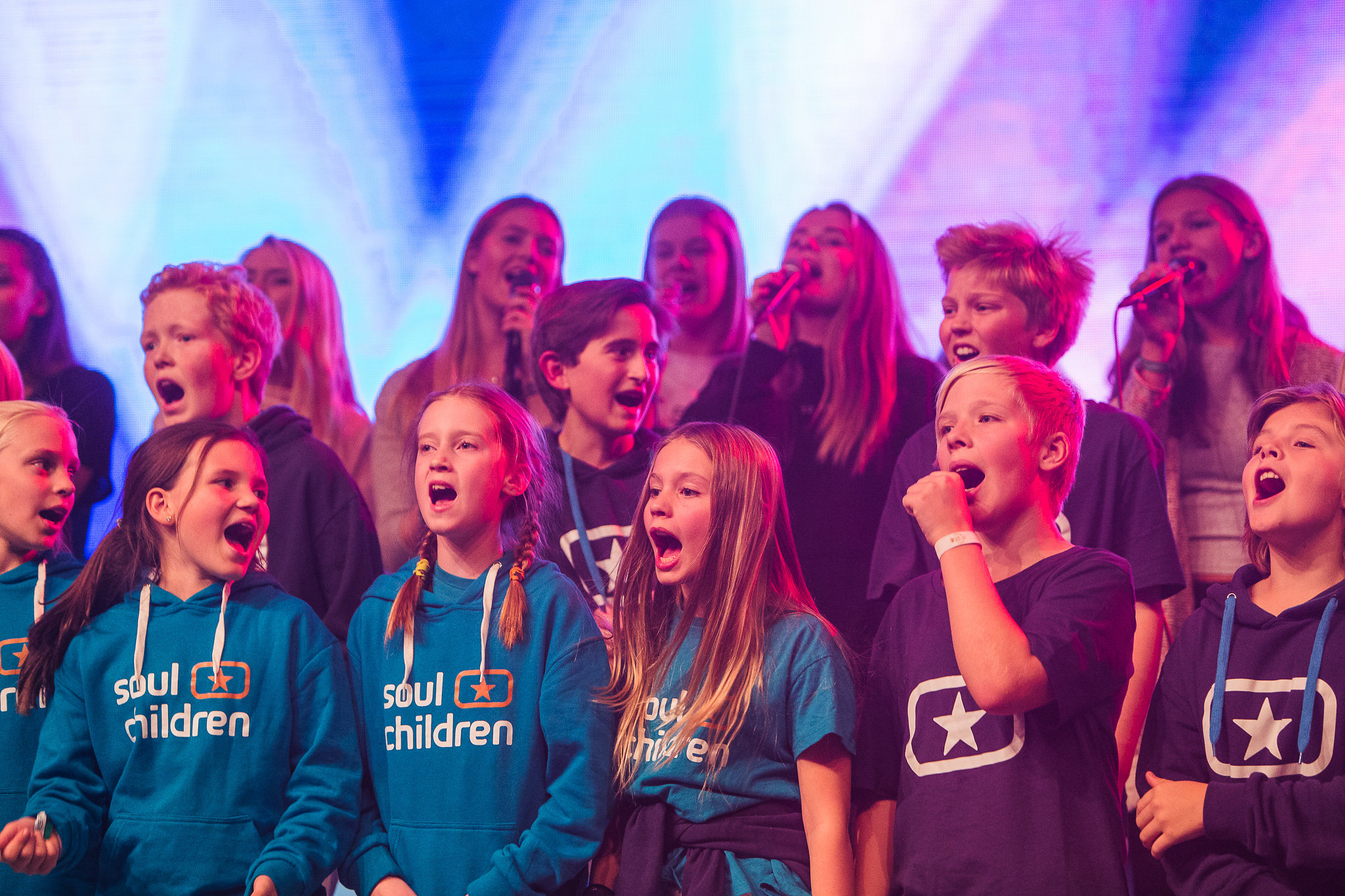 En barn - och ungdomskör som står på en scen och sjunger. 