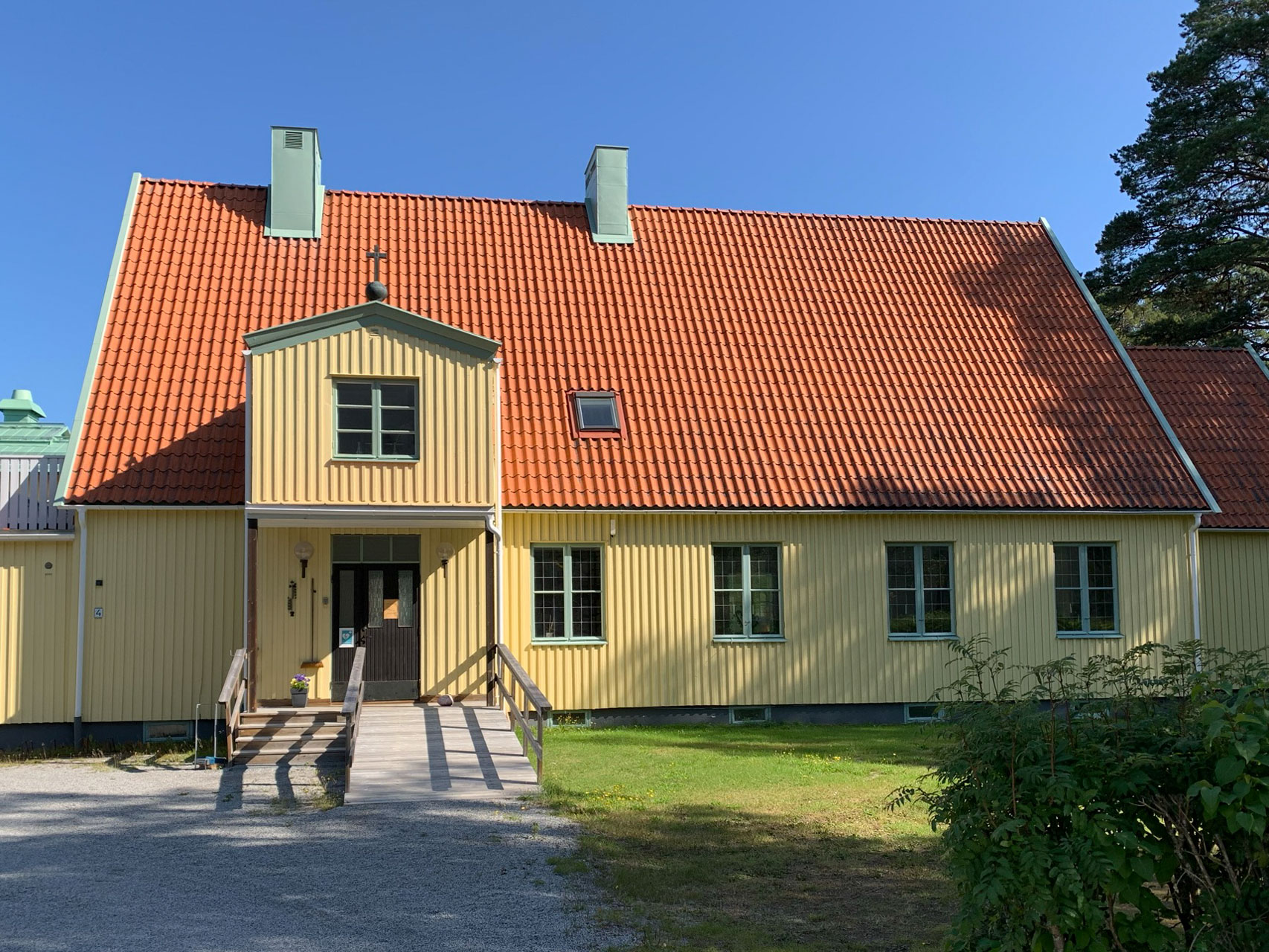 En byggnad med stående gul träpanel och tegeltak.