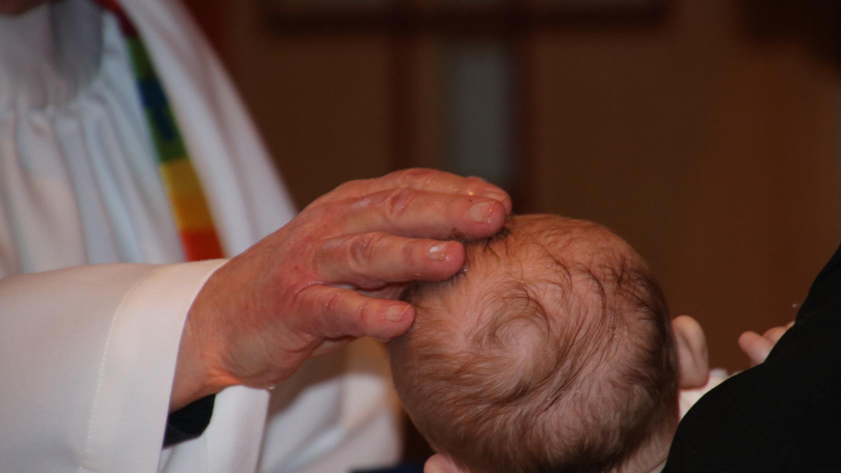 Prästens hand på dopbarnets huvud