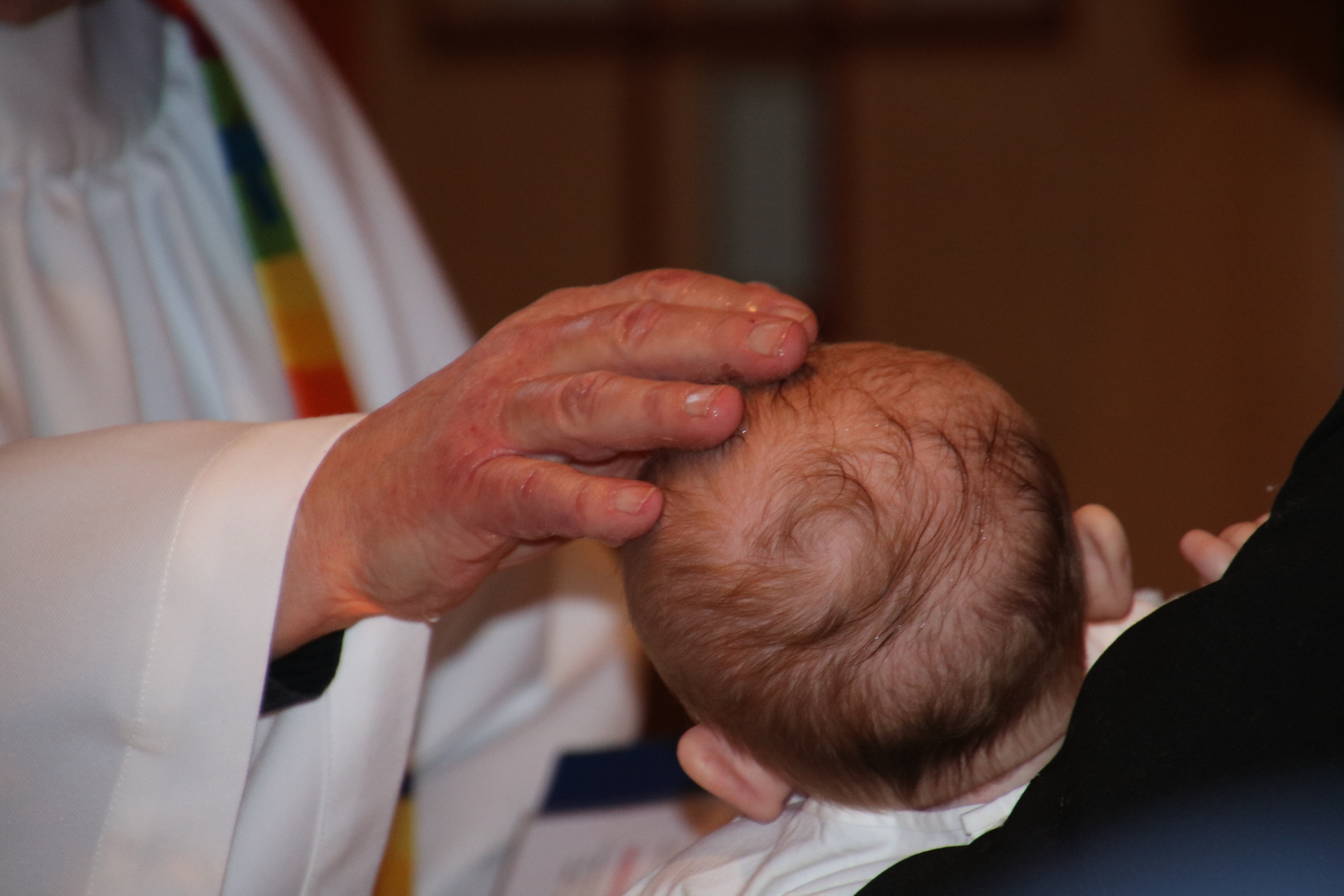 Prästens hand på dopbarnets huvud