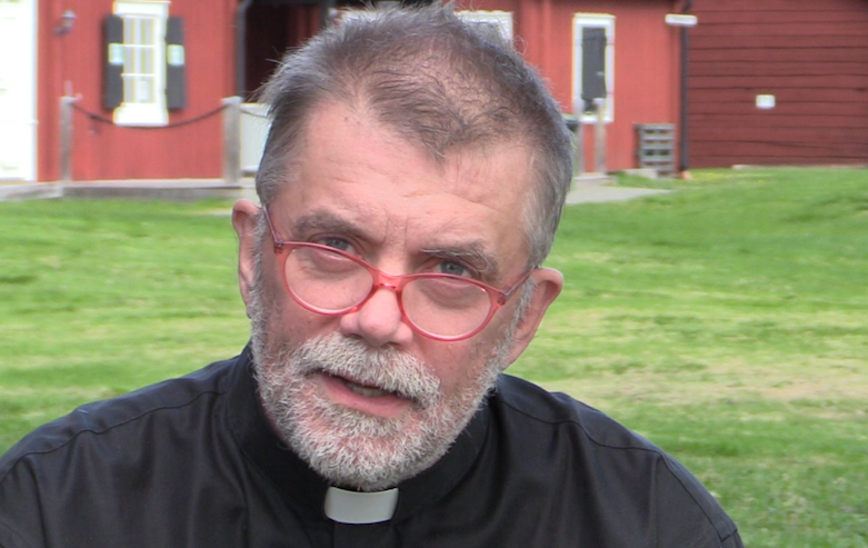 Arne Andersson håller andakt med café Kyrkholmen i bakgrunden