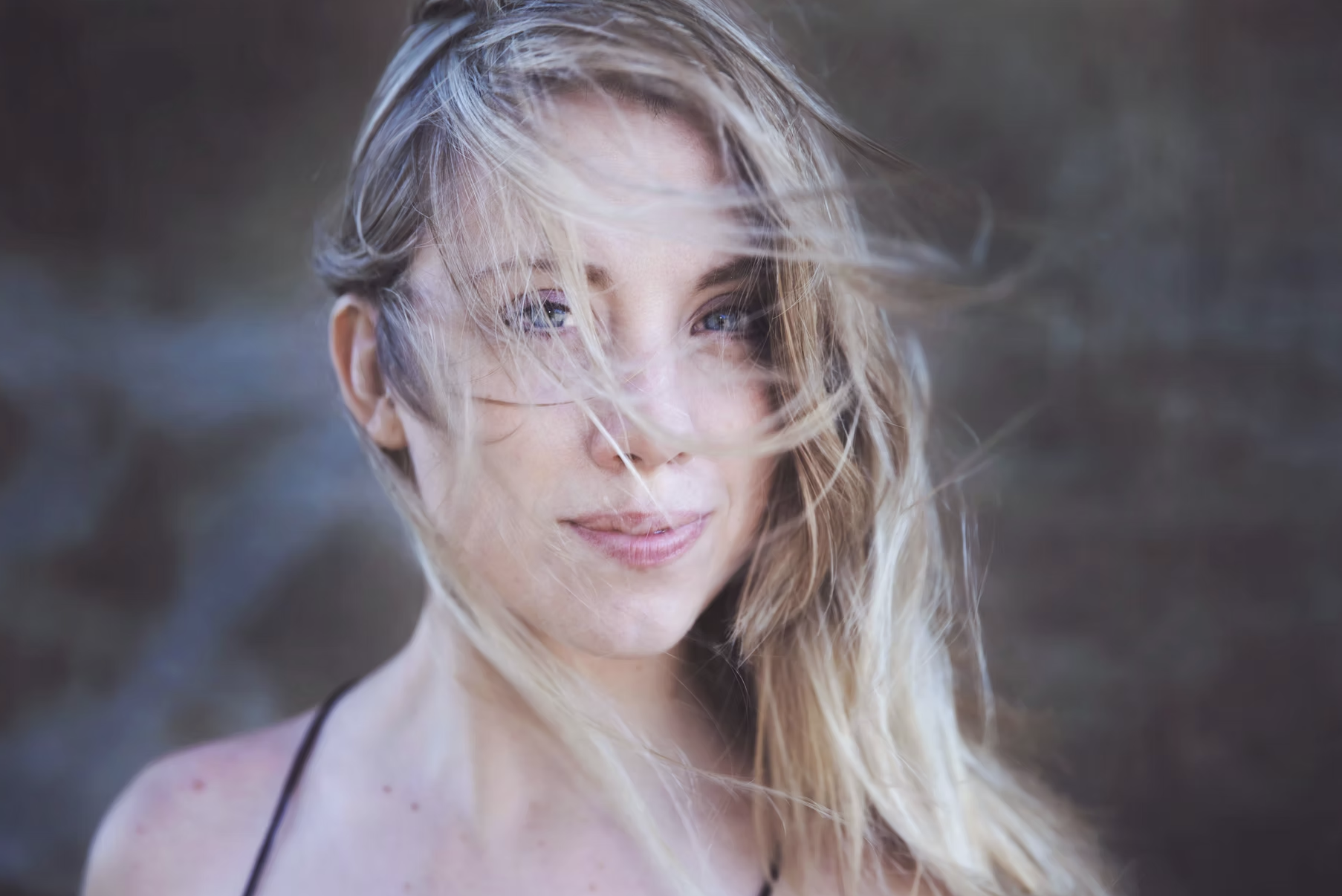 Bild på sångerskan Jenny Almsenius. Närbild med Jenny. Långt ljust hår som vinden tagit tag i och döljer delar av ansiktet