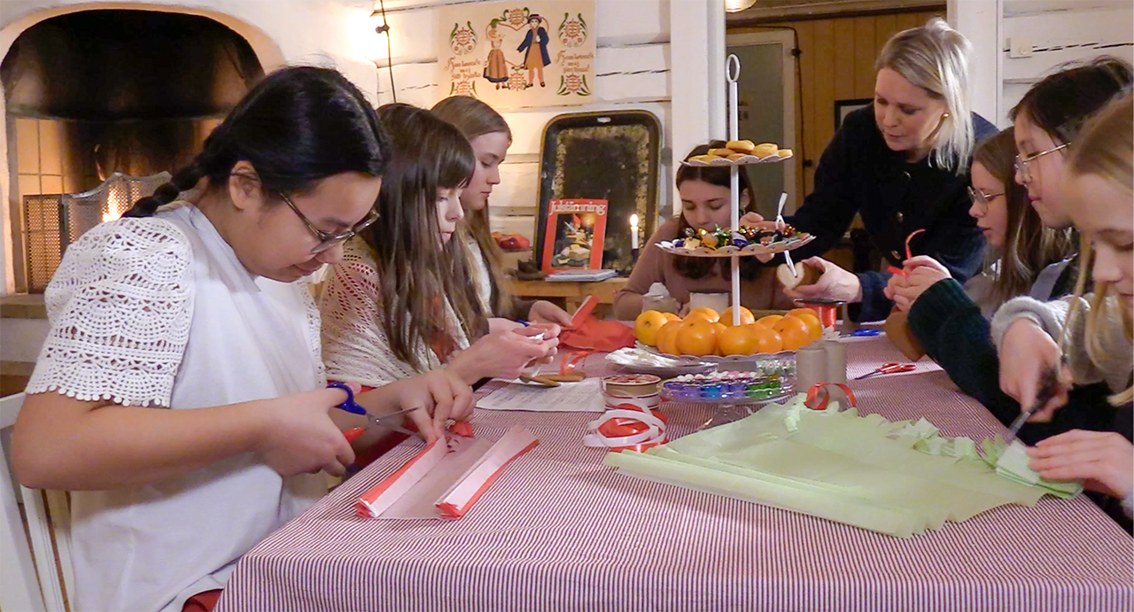 Barn från Lejonströmskören julpysslar vid ett bord i Ryggåsstugan på Stiftsgårdsområdet i Skellefteå. 