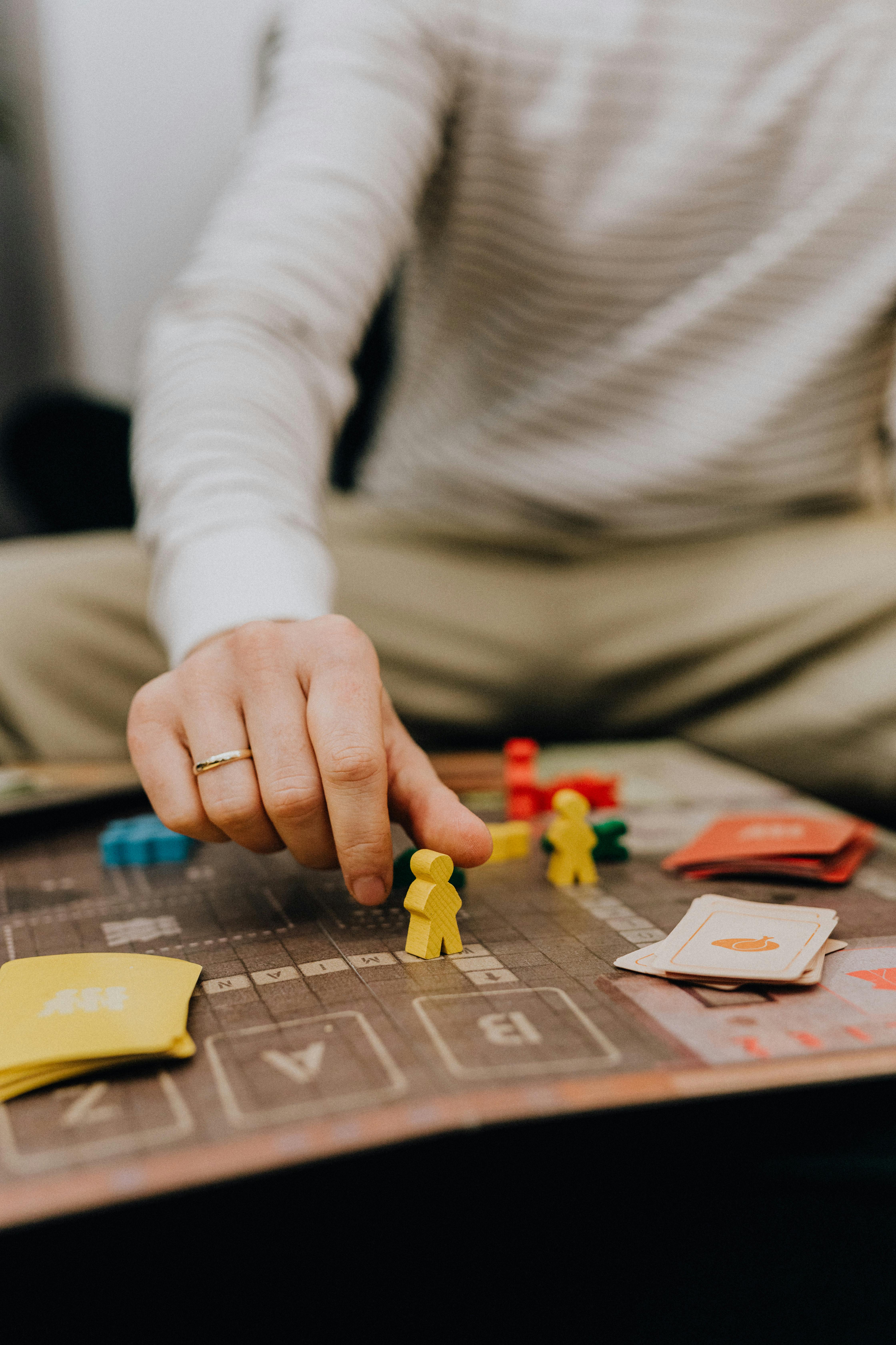 bilden visar en person som spelar brädspel, man ser händerna och spelpjäserna.
