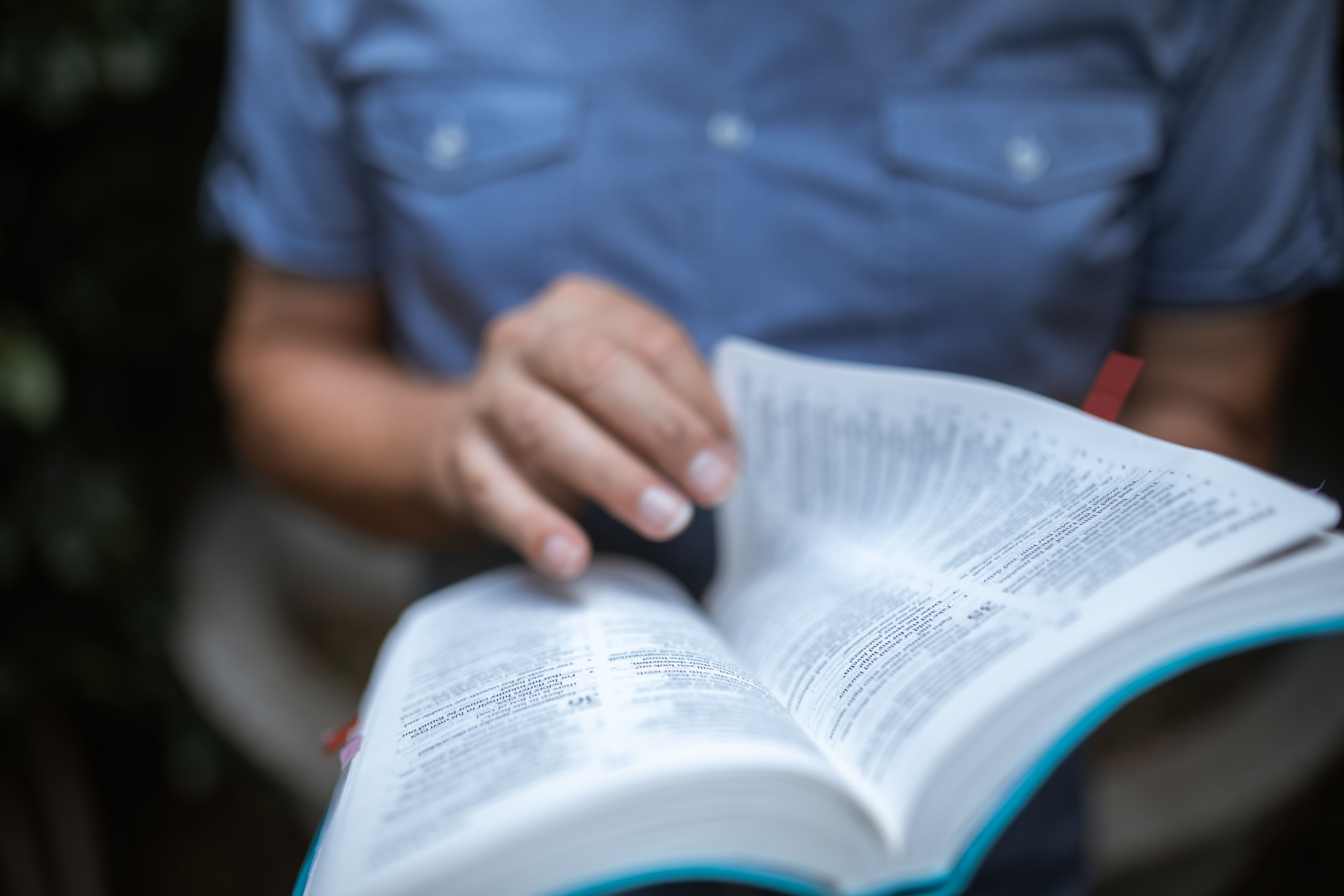 Bilden föreställer en person som bläddrar i en bibel i närbild