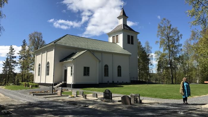 Exteriörbild av Trehörningsjö kyrka med grönskande bakgrund.