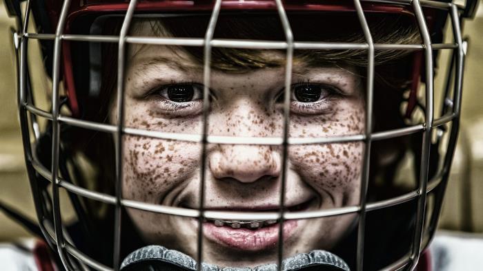 Ett ansikte på ett barn som har en hockeyhjälm på sig.