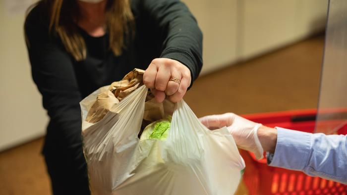 En person överräcker en matkasse till en annan person