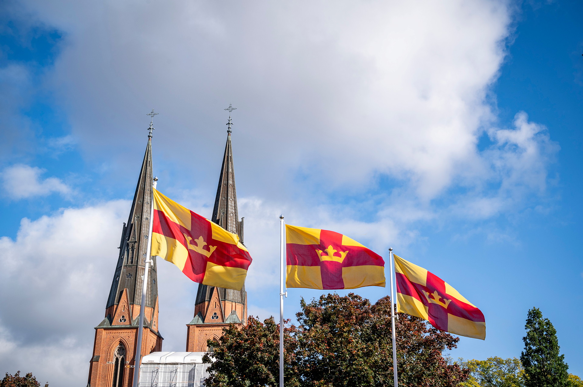 Svenska kyrkans flagga på tre flaggstänger framför Uppsala domkyrka
