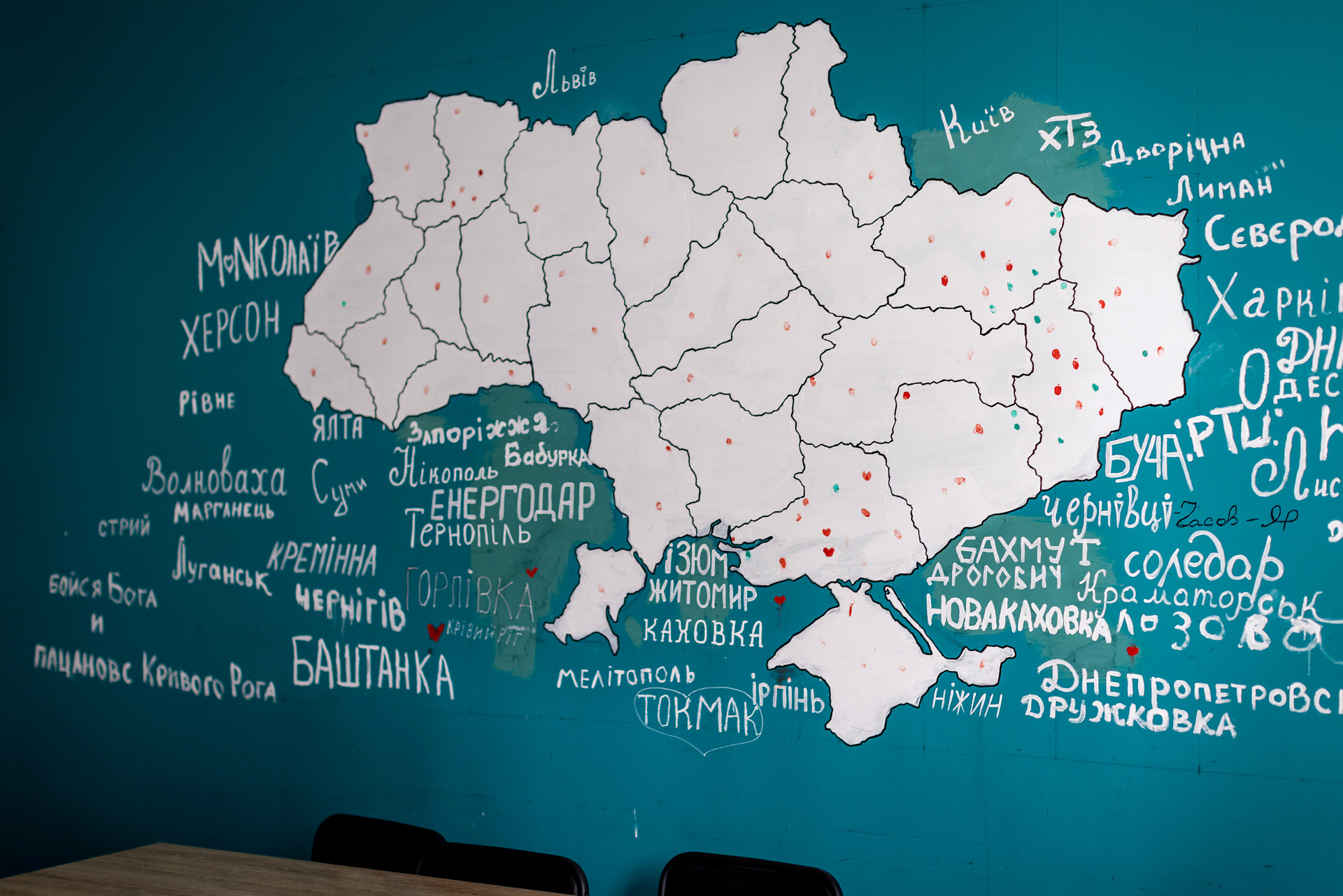 Vi ser en karta över Ukraina med regionernas namn utskrivna på ukrainska. Landets gränser omges av turkosa färgfält.