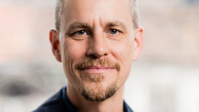 Porträtt på nära håll av Benjamin Åberg i blå skjorta och med välansat ljust skägg.