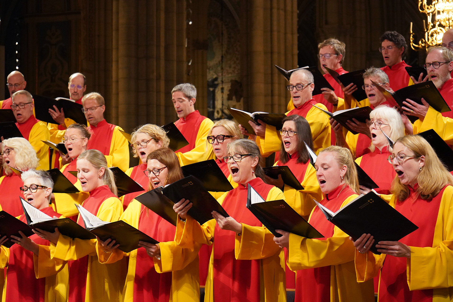 Kören Collegiuym Cantorum sjunger ut i Uppsala domkyrka, iförda sina röda och gula körkåpor och med notpärmarna i högsta hugg.