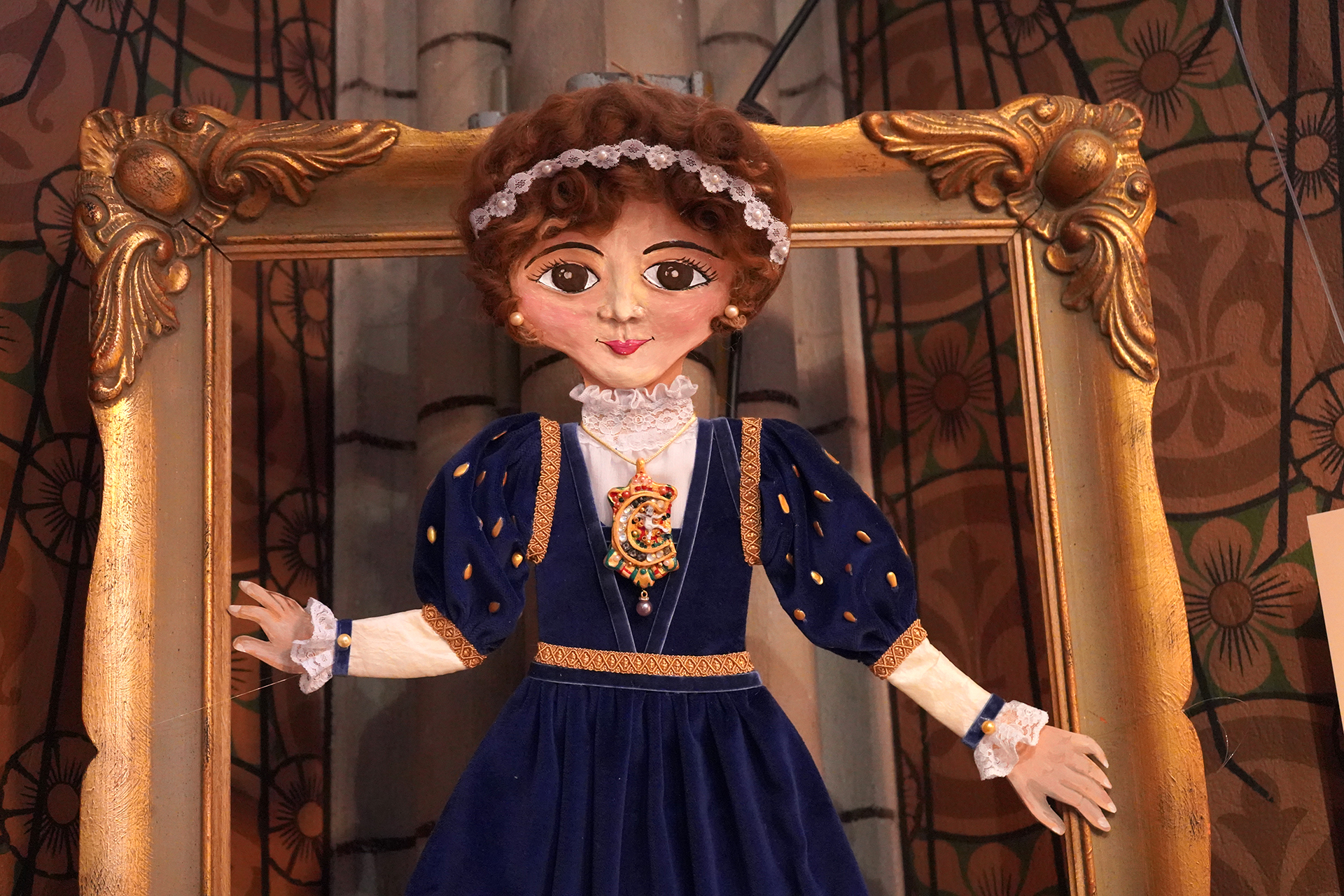 Drottning Katarina Jagellonica skildrad som tecknad figur och placerad i en praktfull ram i Uppsala domkyrkas barnkör. Hon har blå klänning med gyllene detaljer och brosch.