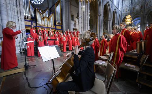 Uppsala domkyrkas flick- och gosskörer i korsmitten i Uppsala domkyrka, där de dirigeras av Margareta Raab. alla är klädda i röda körkåpor.