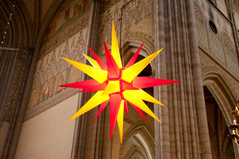Uppsala domkyrkas herrnhutiska julstjärna i lysande rött och guld hänger under de höga valven.