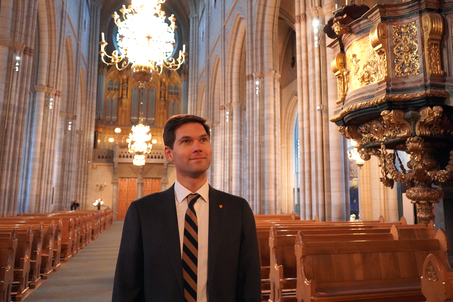 Robert Bennesh, organist, porträtterad i Uppsala domkyrkas mittgång med blicken upp mot valven.