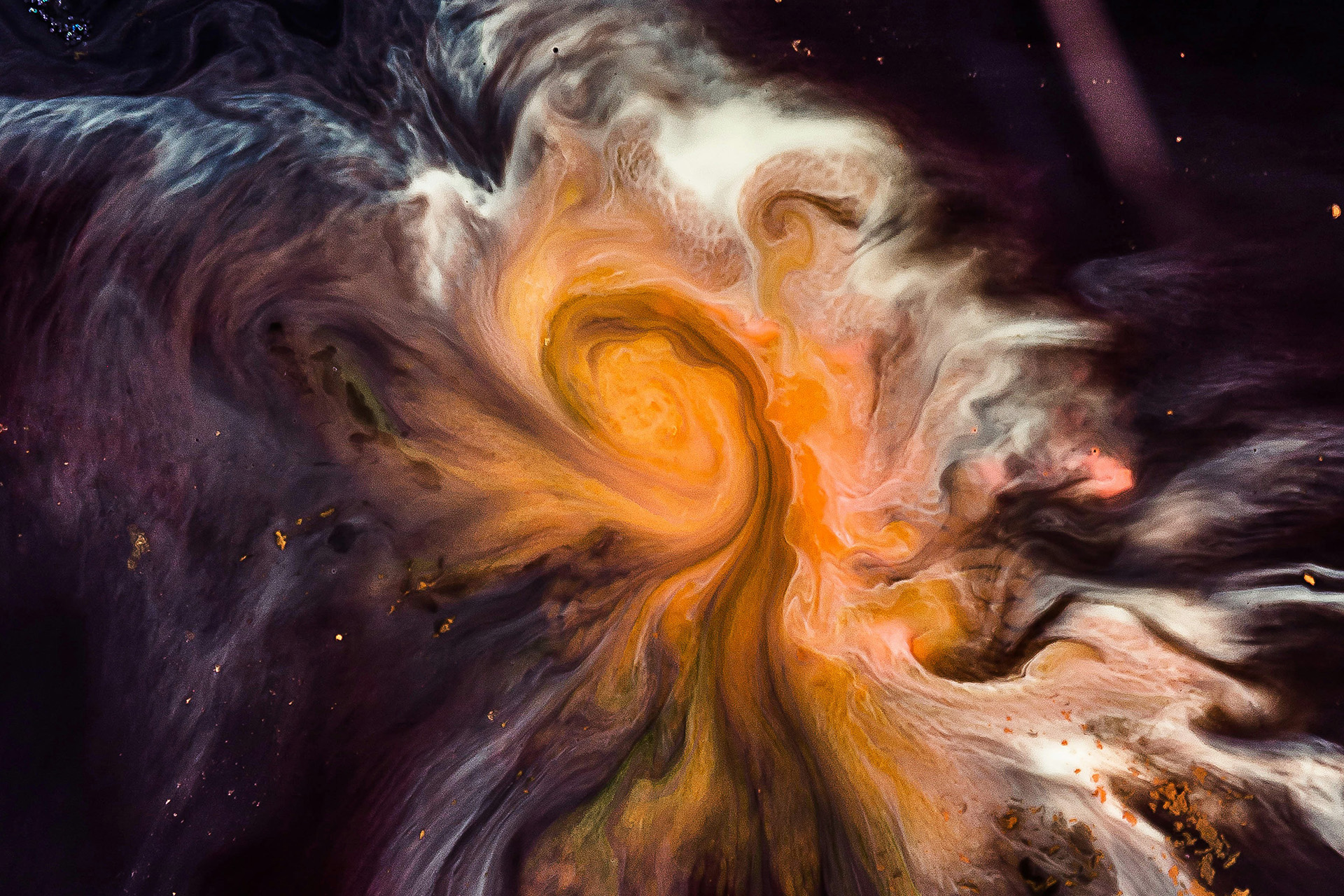 Ett färgrikt foto av rymden och vad som tycks vara en virvlande nebulosa i oranga och vita nyanser mot mörk bakgrund.