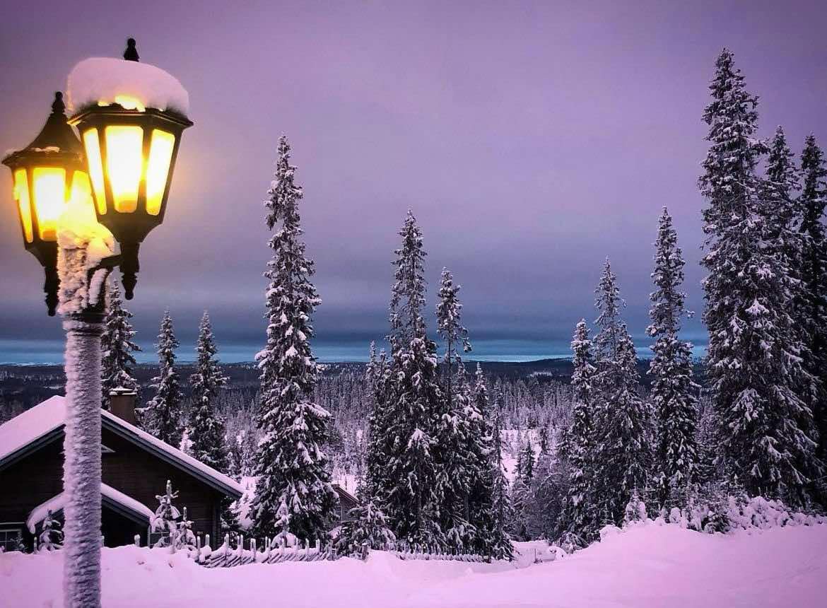 Lykta som lyser vinterlandskap, vackra färger i solnedgång