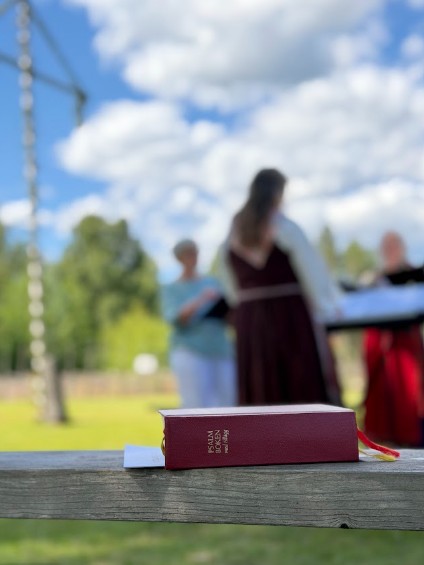Psalmbok i förgrunden, sjungande kör i bakgrunden