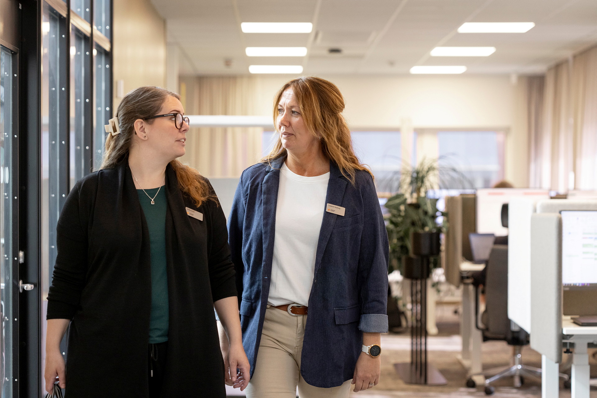 Två kvinnor pratar i kontorsmiljö. 