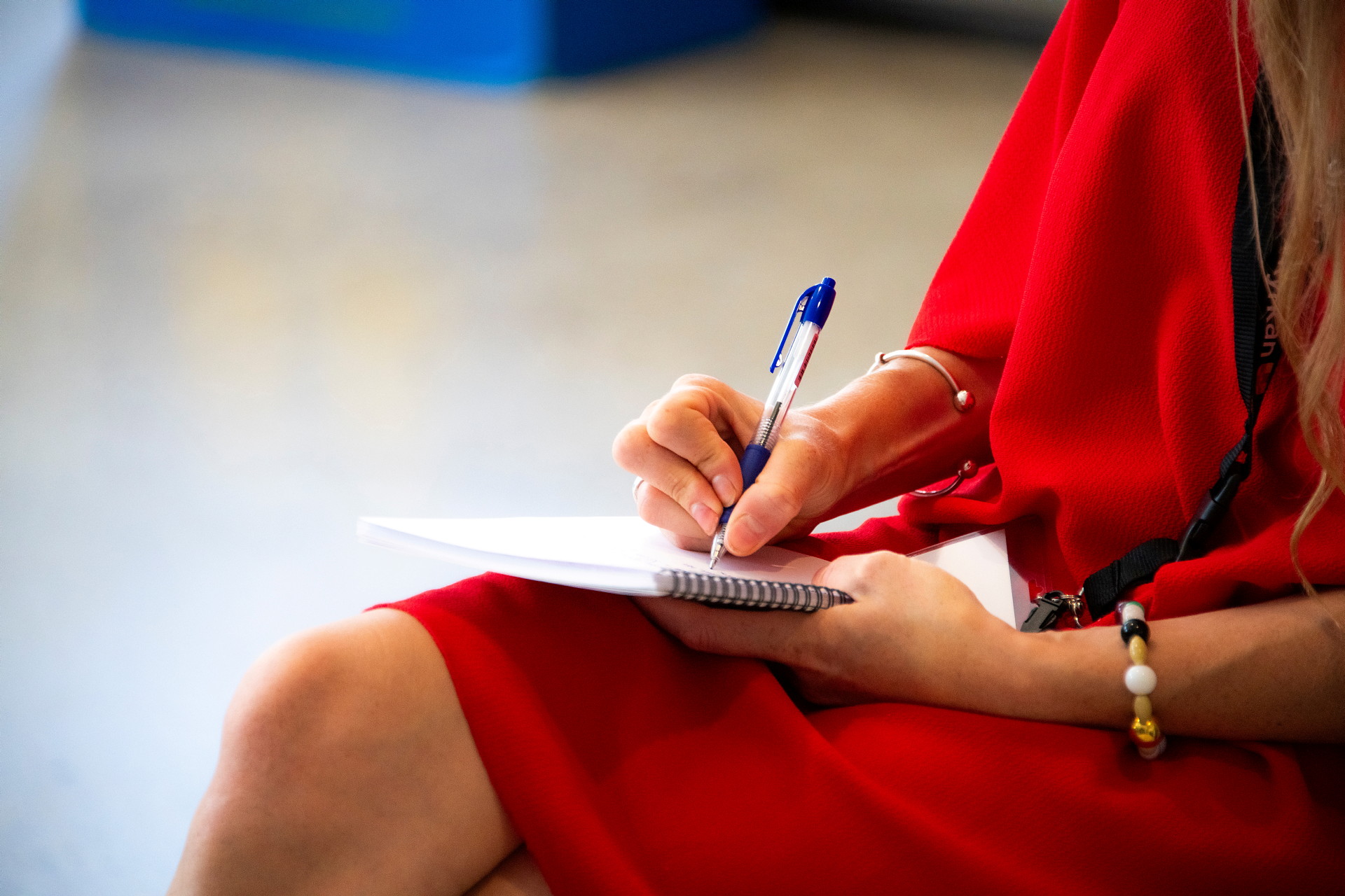 En kvinna sitter och antecknar i ett block. 